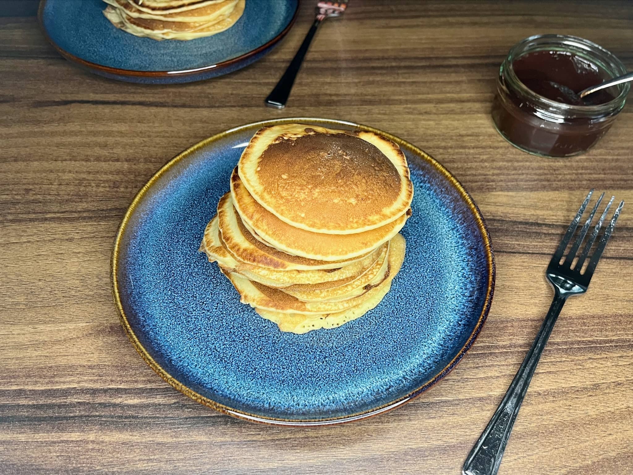 American pancakes in stack on a plate with jam on a side
