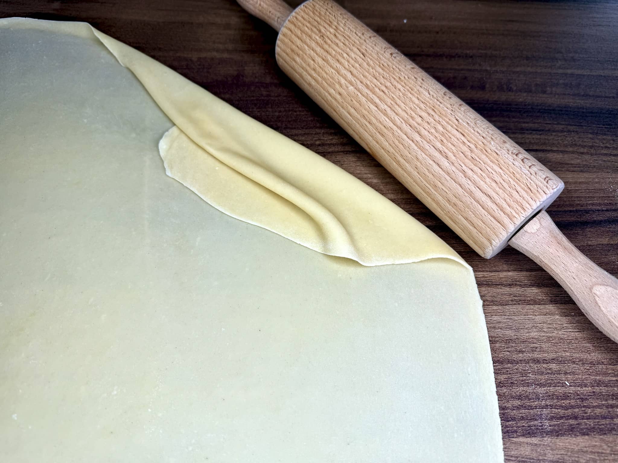 Nicely thinly rolled dough with rolling pin on the side