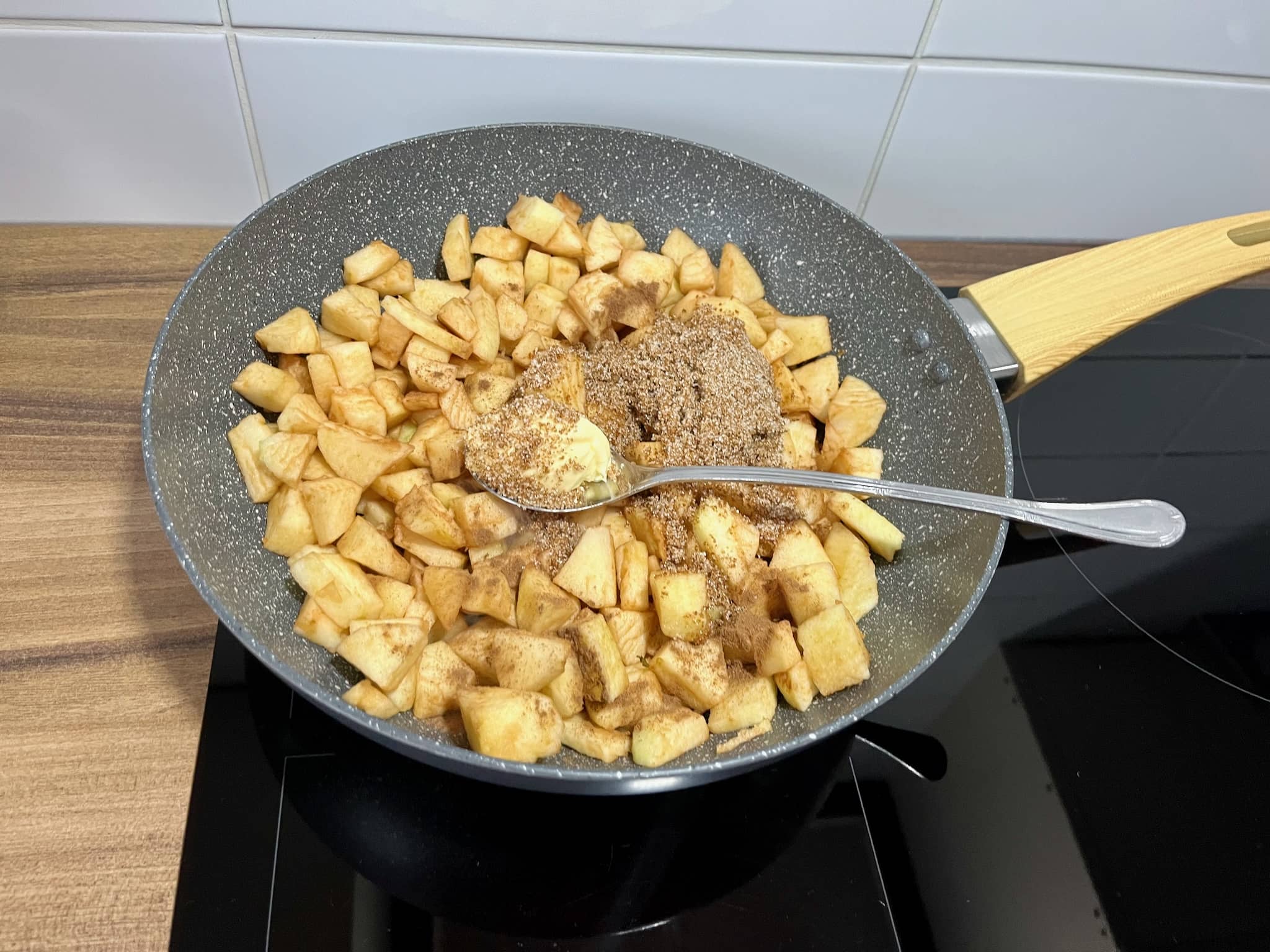 Apples in a frying pan with spices and butter on top