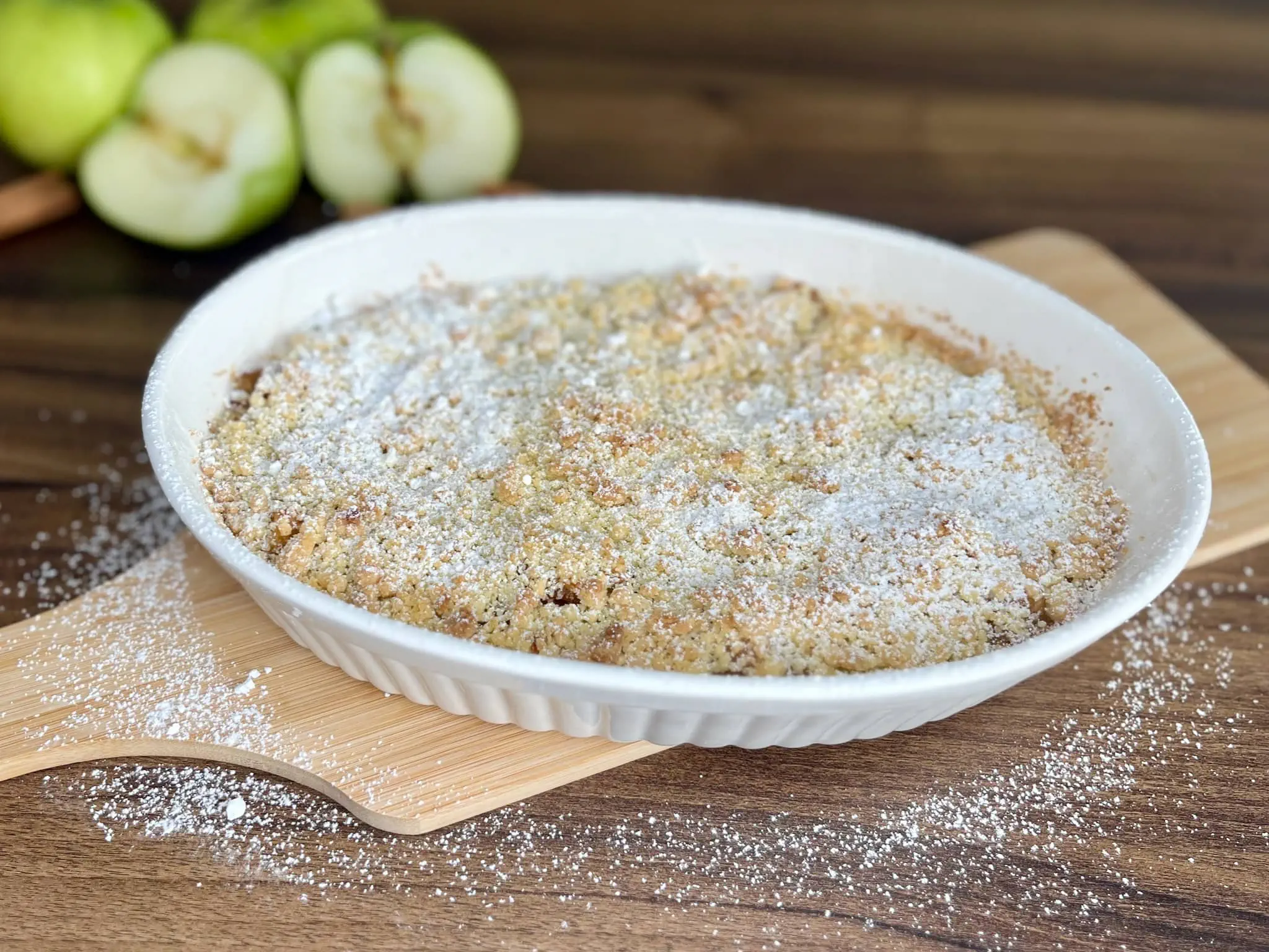 Pięknie upieczona i posypana cukrem pudrem kruszonka jabłkowa w naczyniu do pieczenia