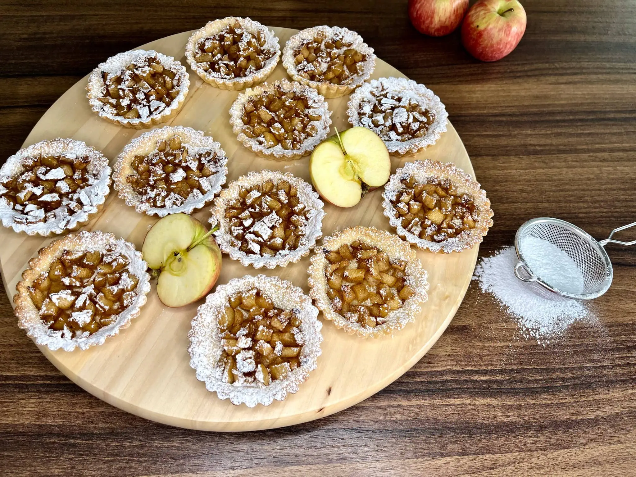 Nicely presented Apple Mini Tarts, dusted, on a chopping board