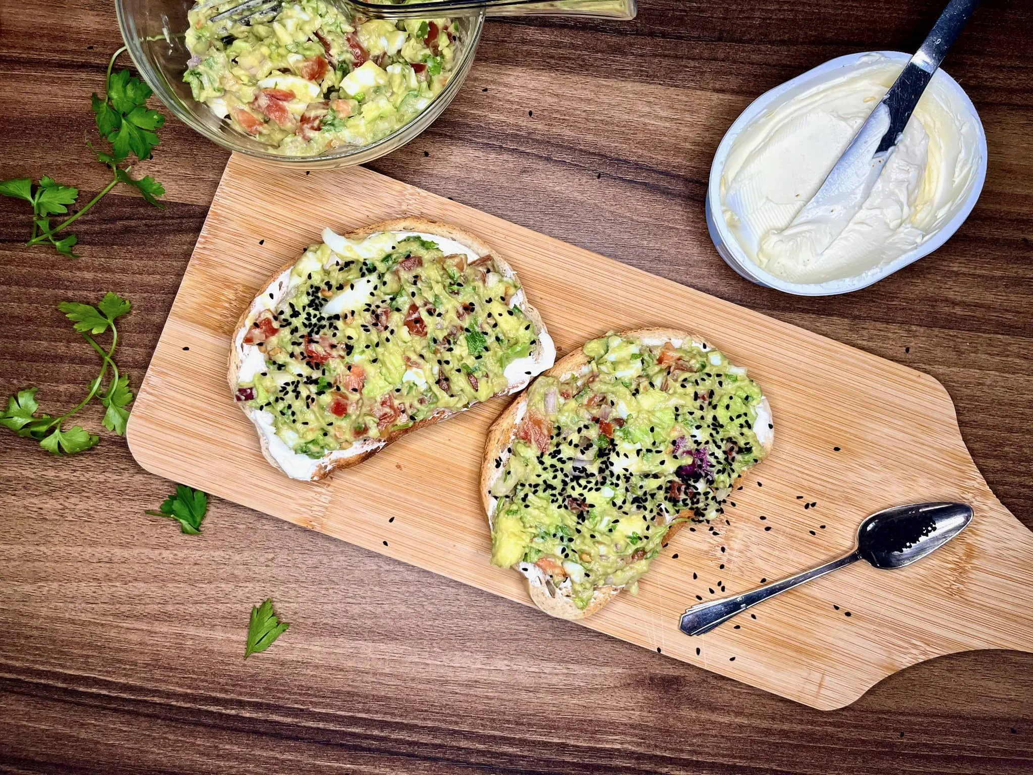 Two Sandwiches with Avocado and Egg Salad on a chopping board