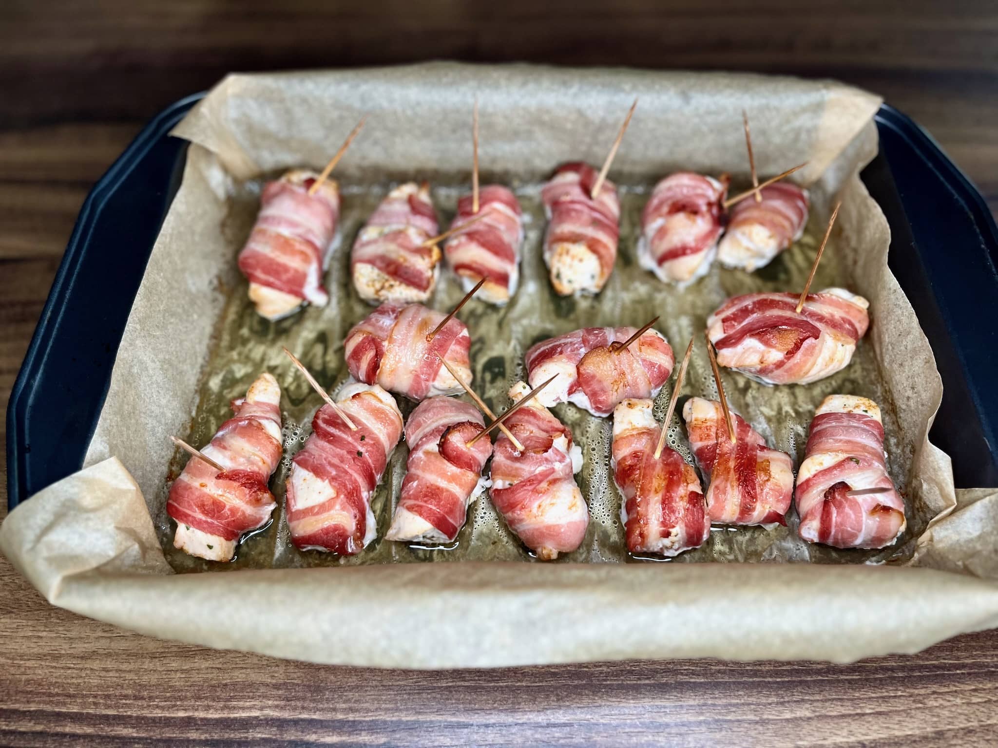 Golden-brown Bacon-Wrapped Chicken Bites emerge from the oven, their crispy bacon exterior yielding to juicy, tender chicken within