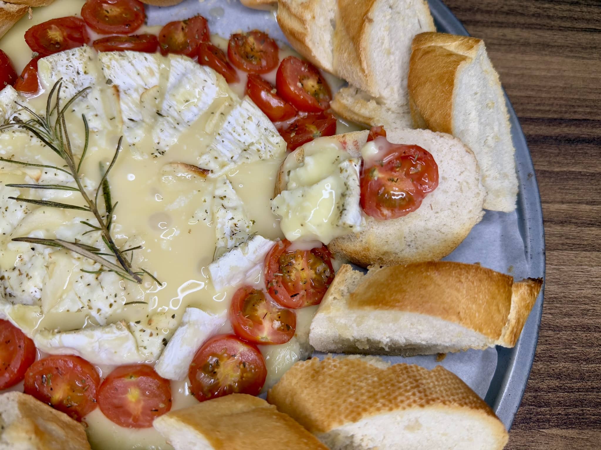 Nicely baked and gooey Camembert with a slice of baguette dipped into it