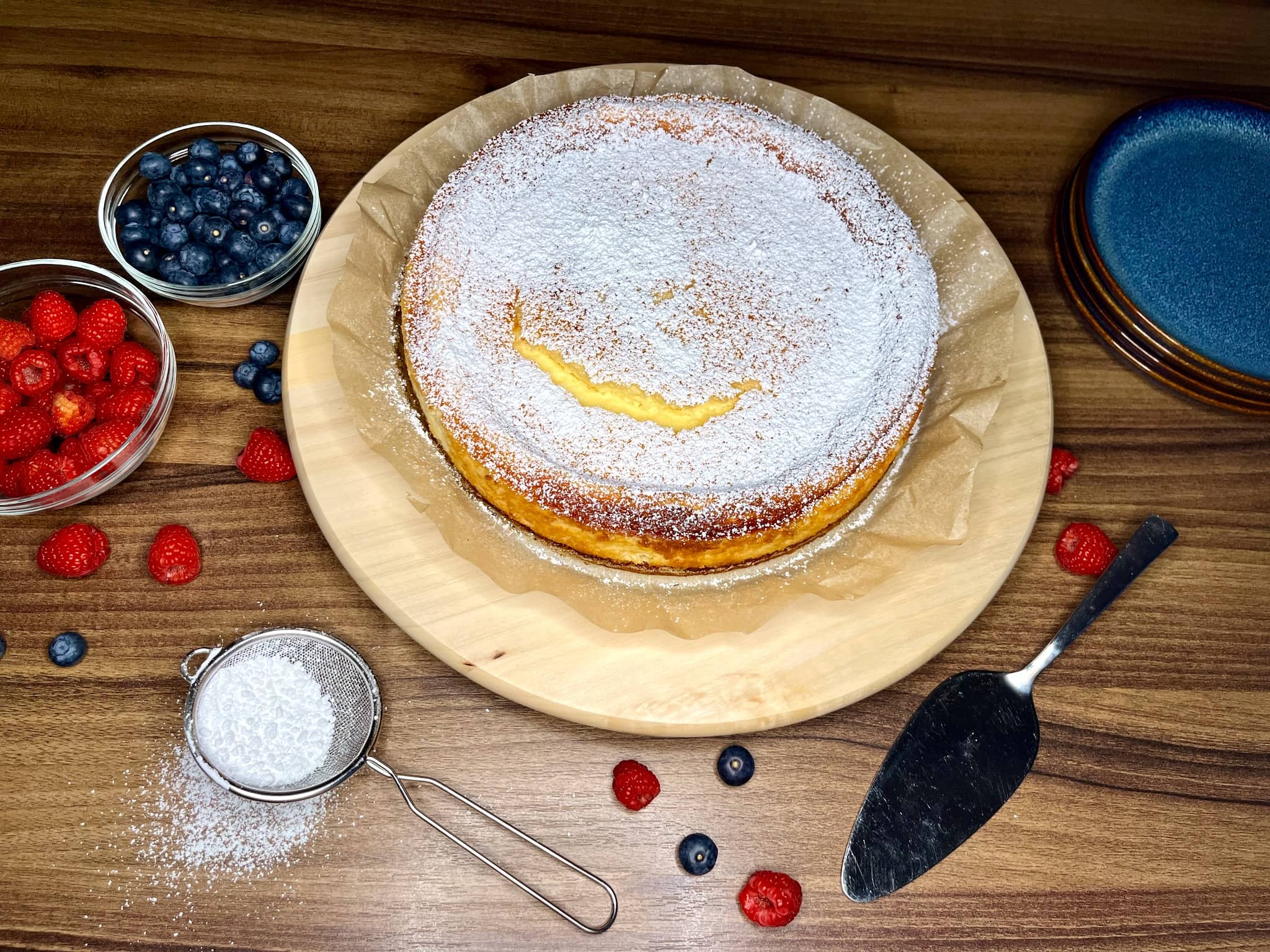 Creamy cheesecake, dusted with sugar, rests on a chopping board