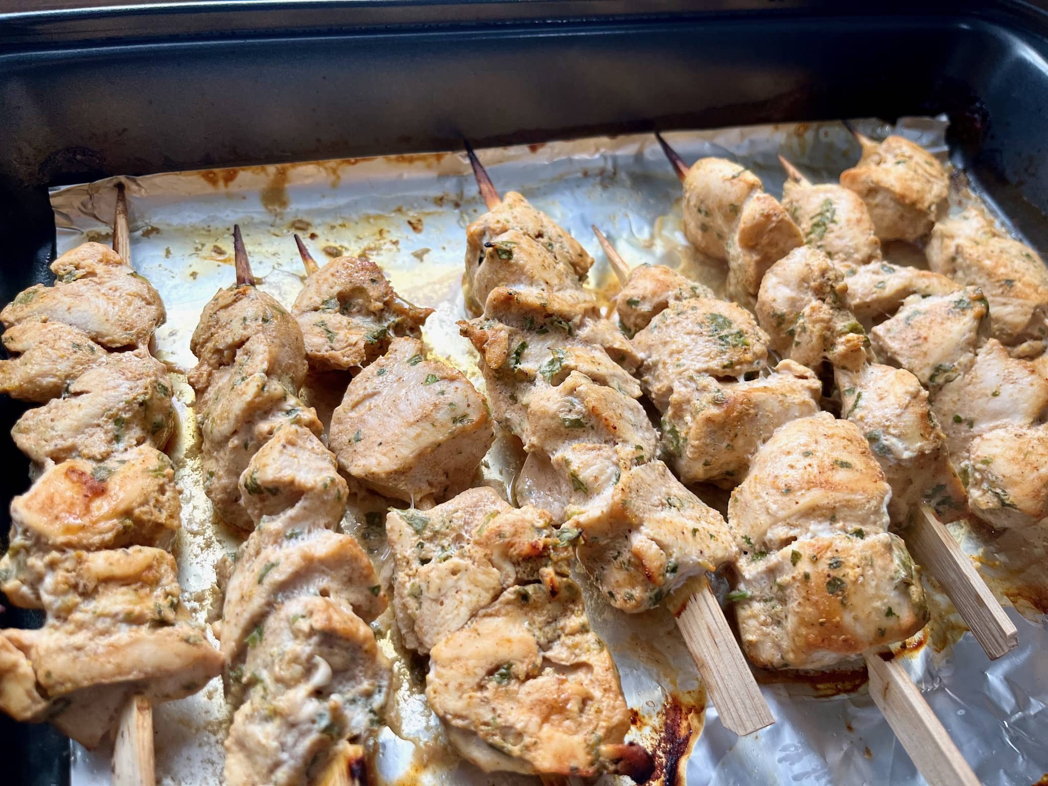 Nicely baked chicken curry skewers, still on in a baking tray