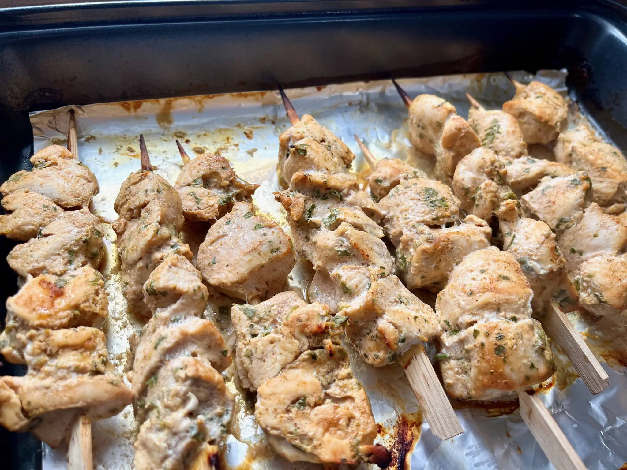 Pięknie upieczone szaszłyki z kurczaka curry, wciąż na blasze do pieczenia