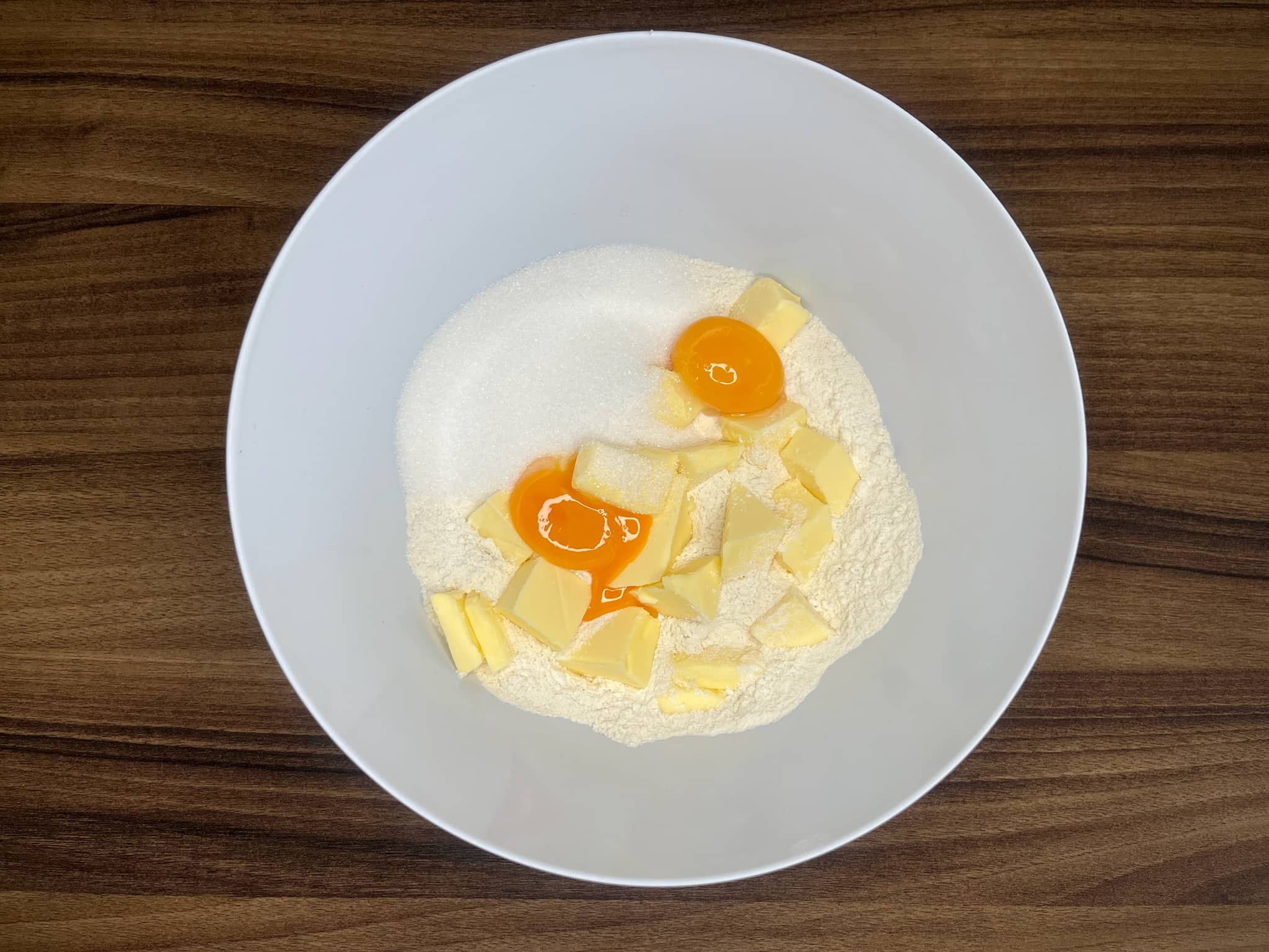 Dry ingredients in a bowl with butter and eggs on top
