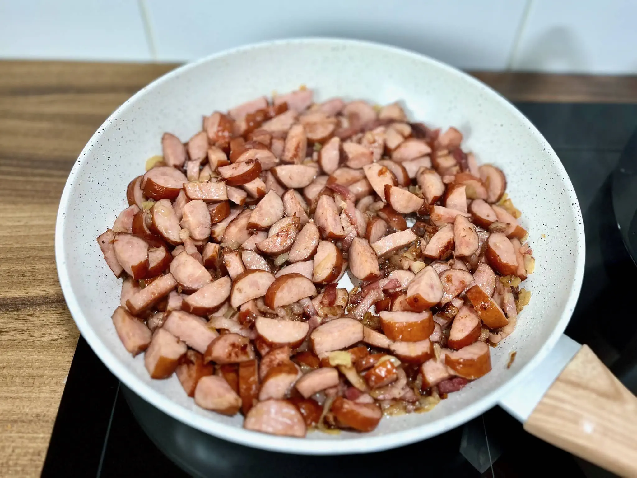 Smażone kiełbasy i boczek na patelni