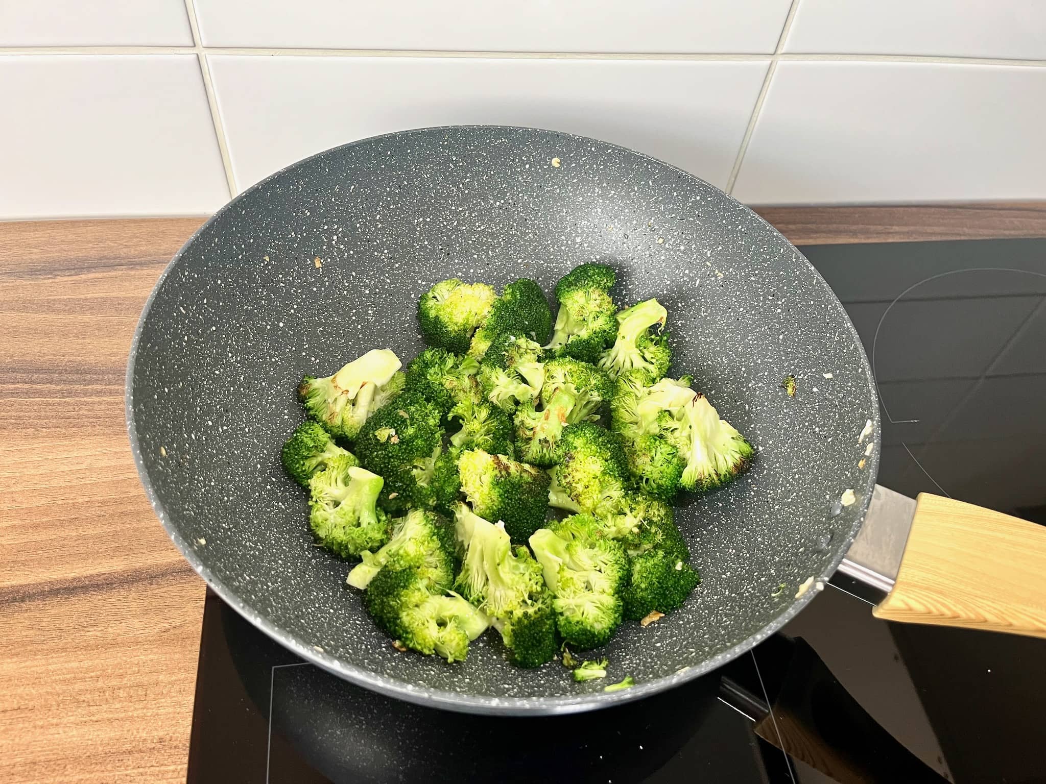 Broccoli florets and garlic frying in a pan
