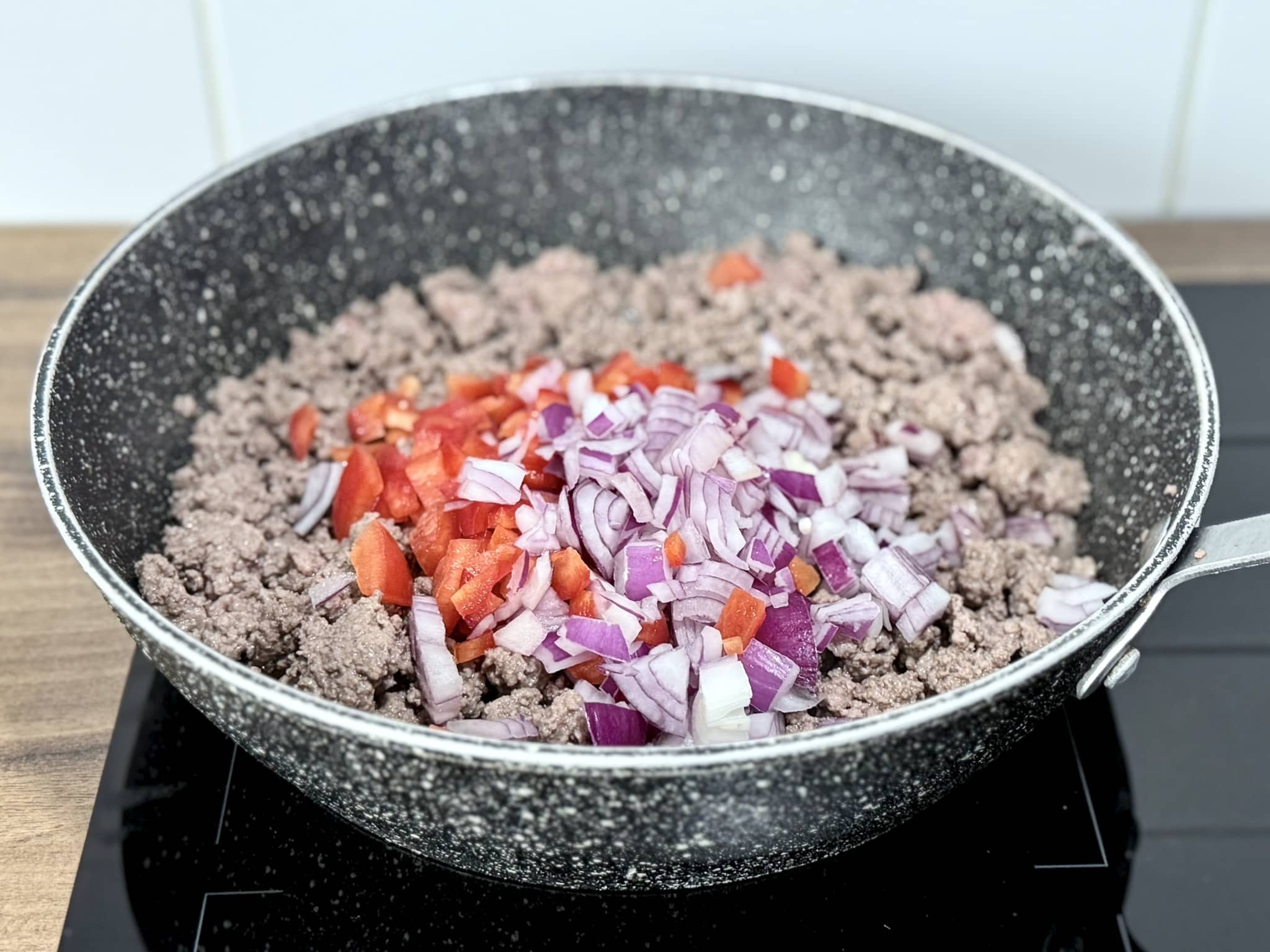 Chopped onion and red bell pepper added to the fried beef mince
