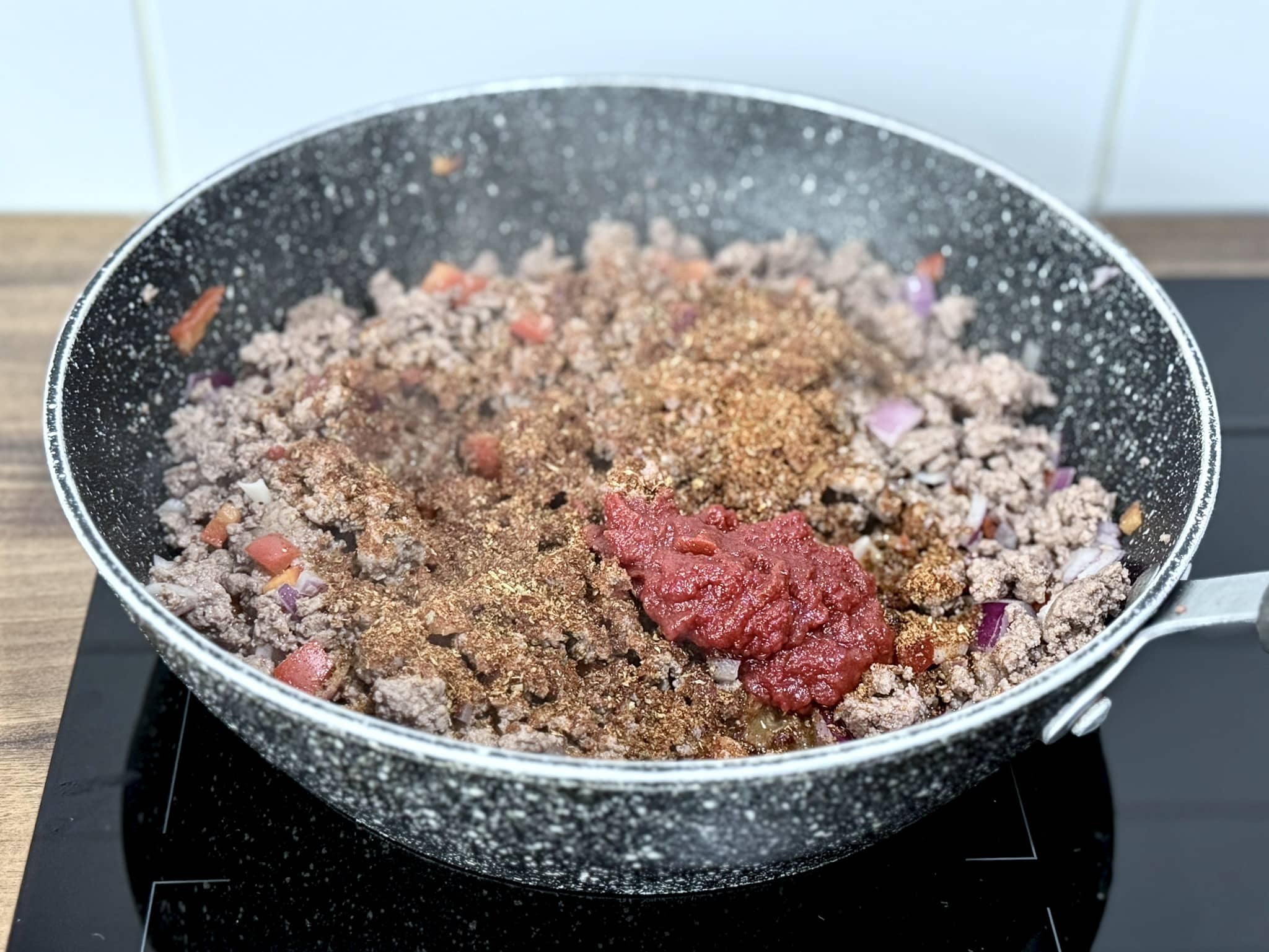 Taco seasoning and tomato paste added to the pan with the beef