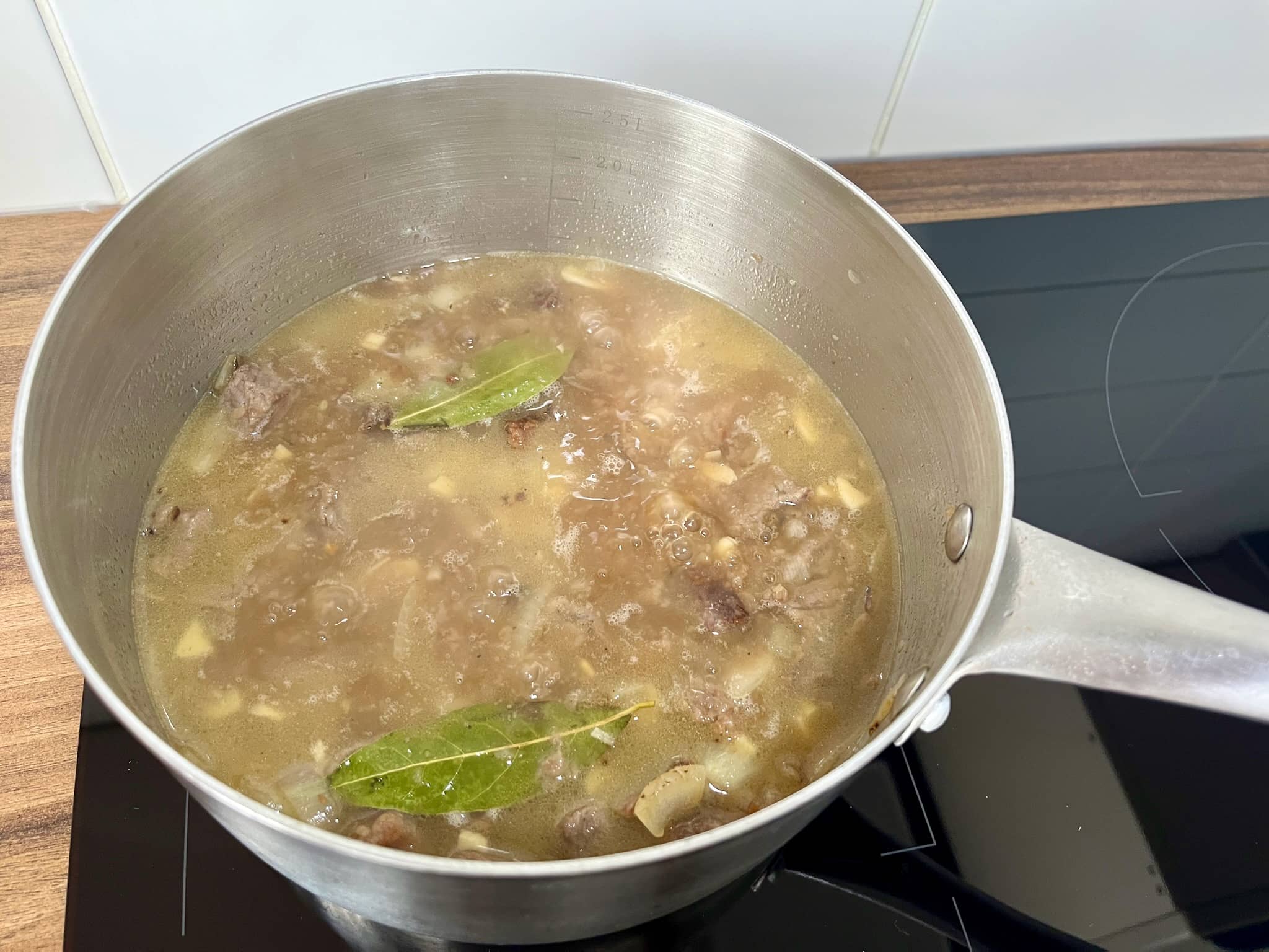 Beef and onion boiling in water with bay leaf and beef stock cube