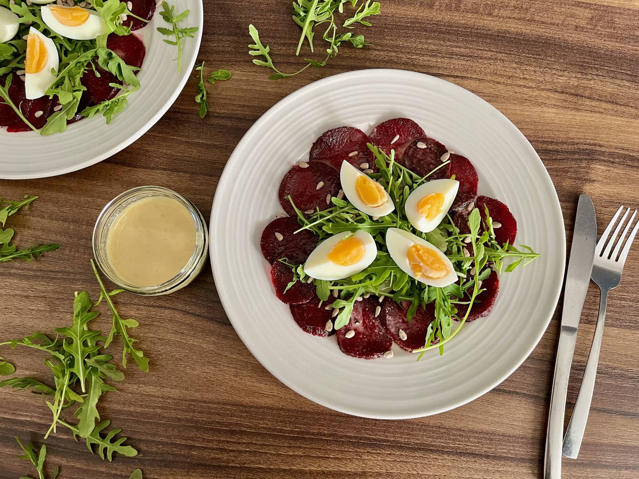 Beetroot Carpaccio on a plate with Wild Rocket leaves and eggs, dressing on a side