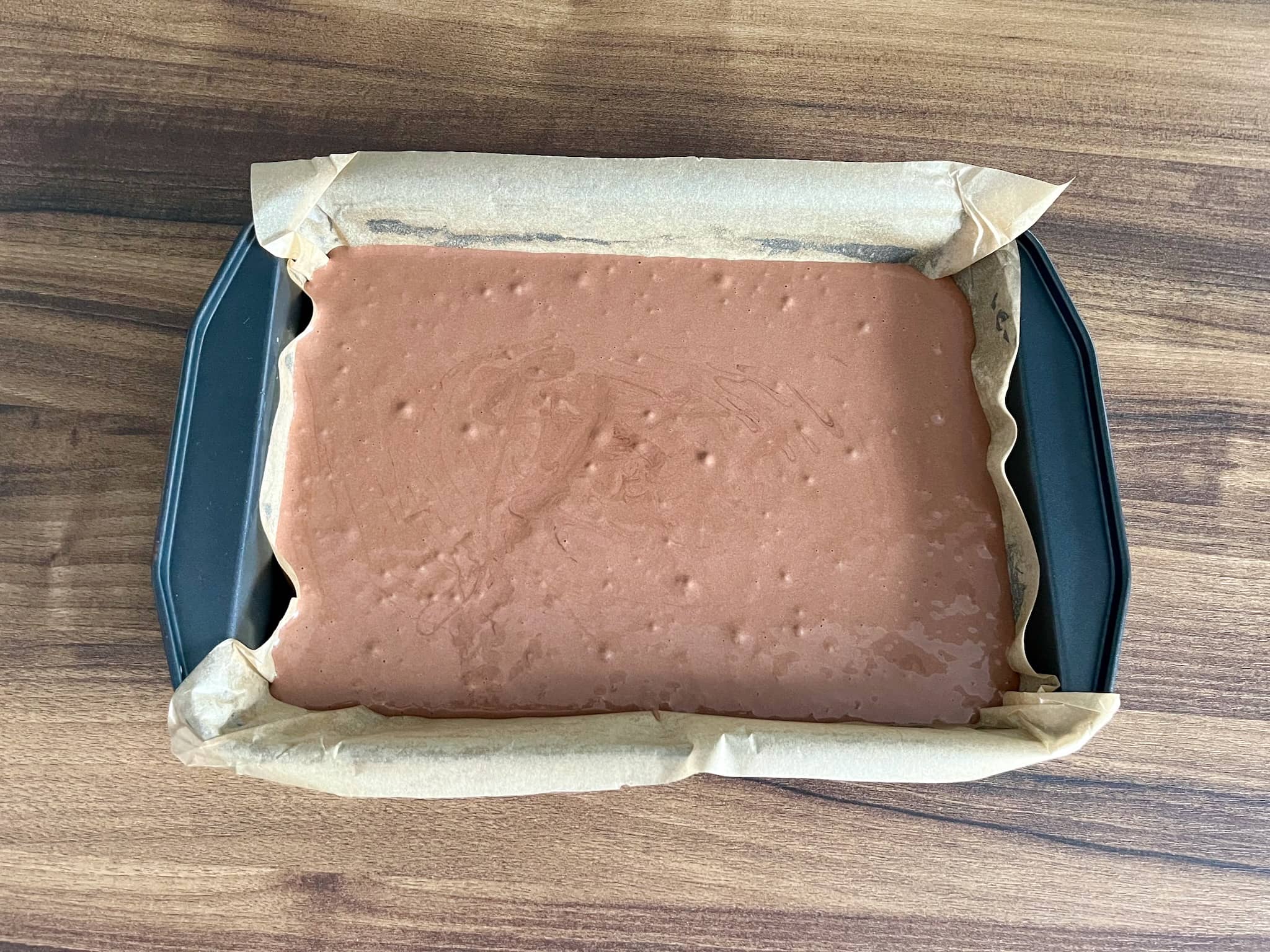 Cake dough in a lined baking tray before baking