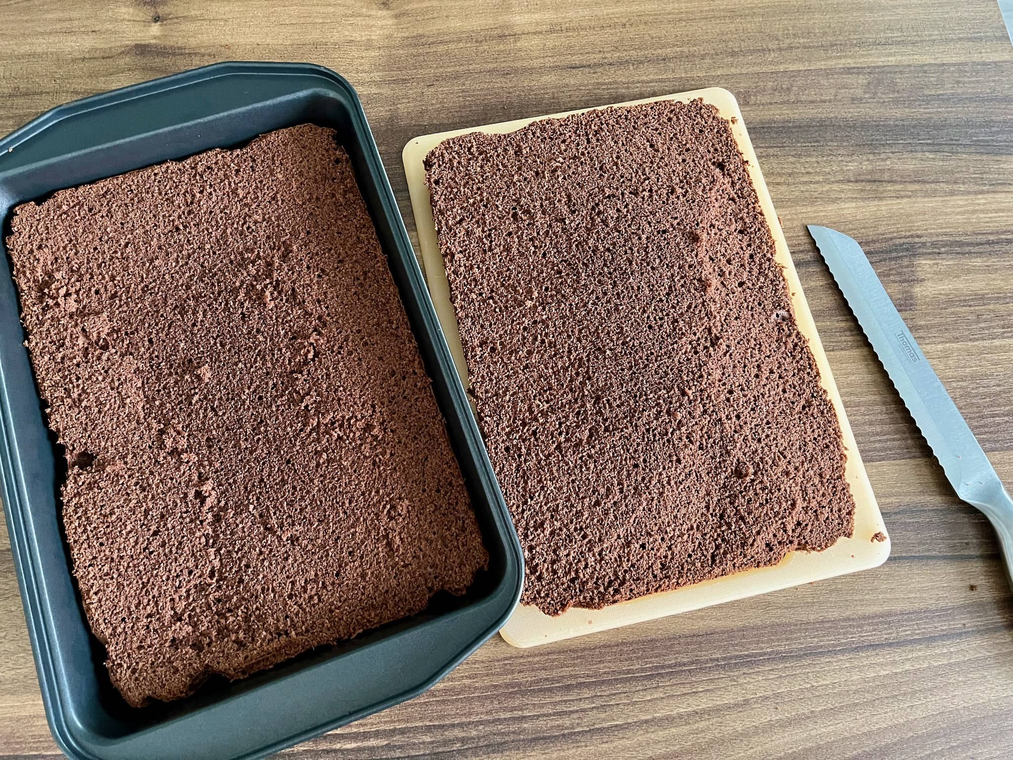 One part of the sponge cake is placed back inside the baking tray and the second is still on a tray on the side