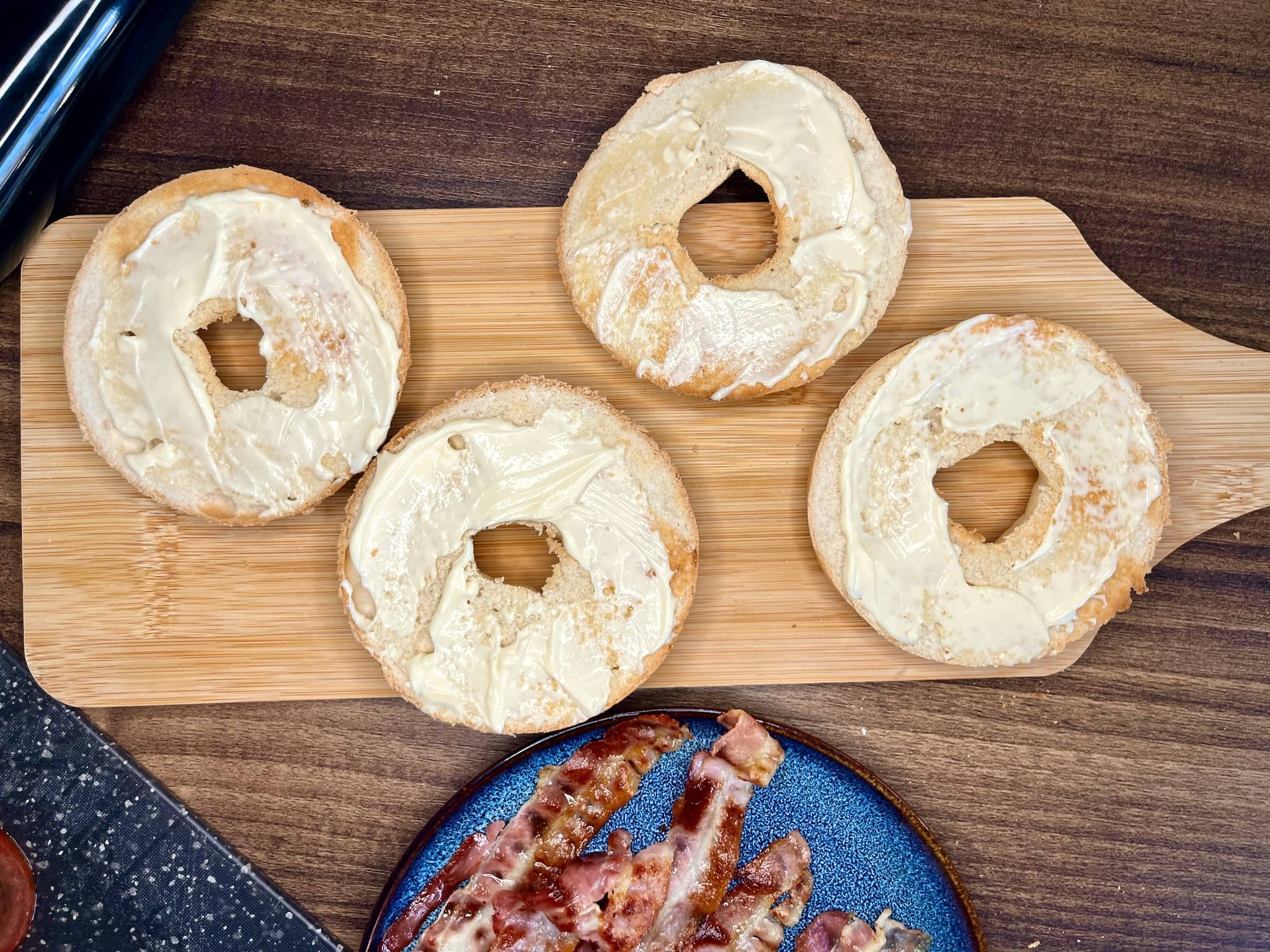 Halves of bagles speaded with mayonnaise lying on a chopping board