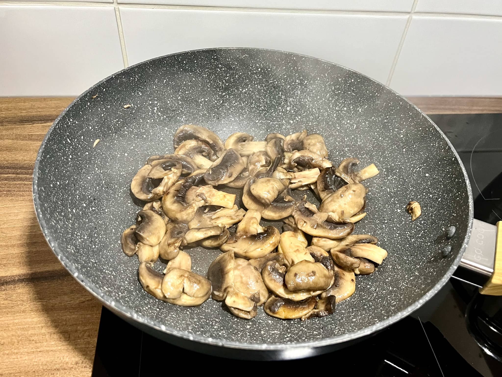 Closed cup mushrooms frying in a pan