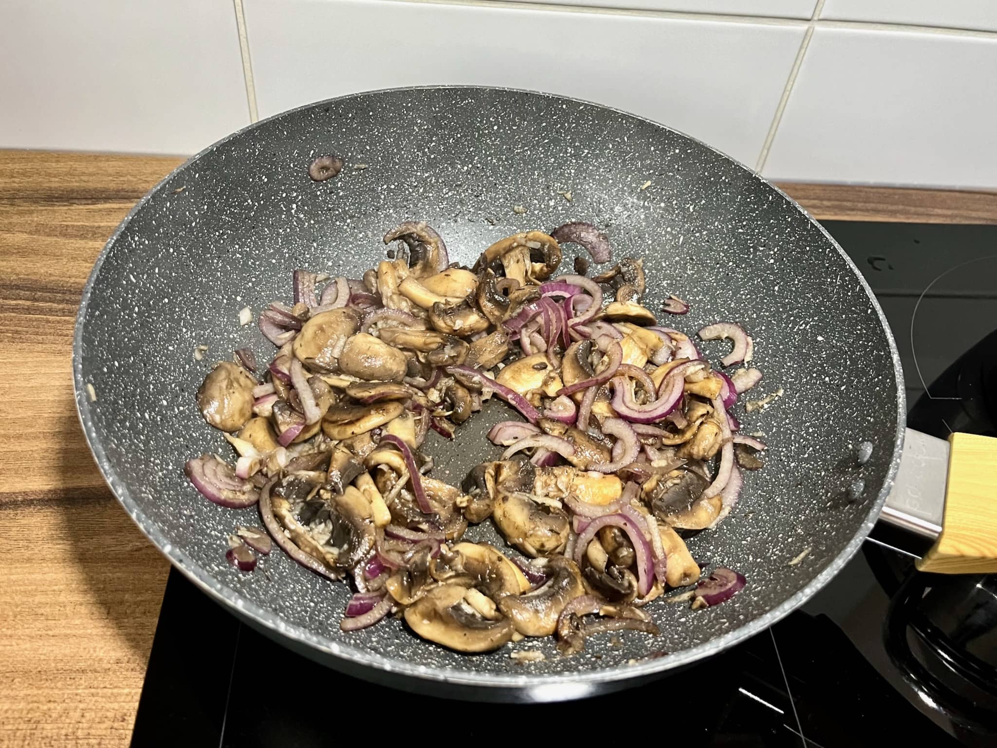 Onion frying in a pan with mushrooms