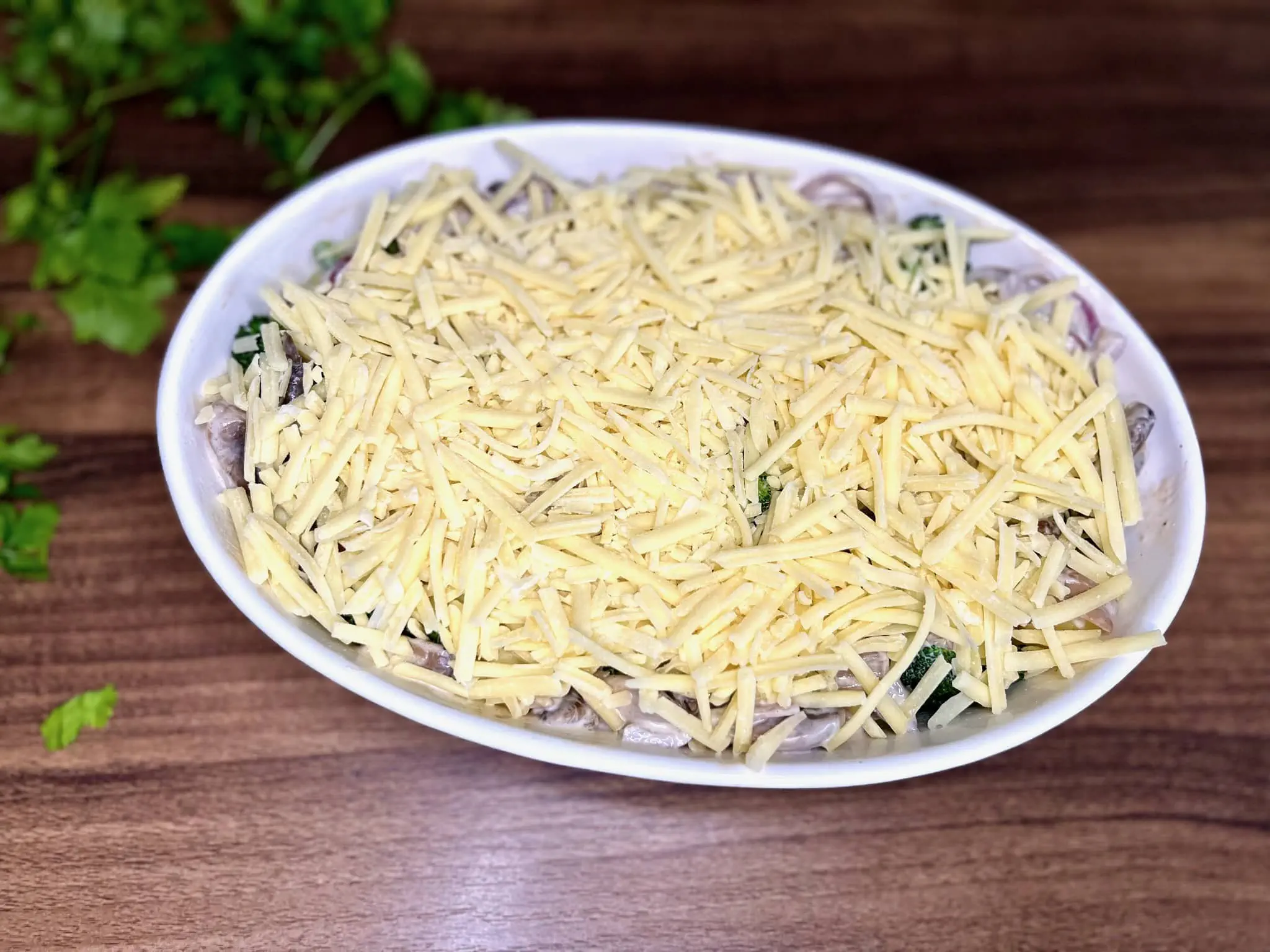 Starty parmezan dodany na wierzch naczynia żaroodpornego ze wszystkimi składnikami w środku