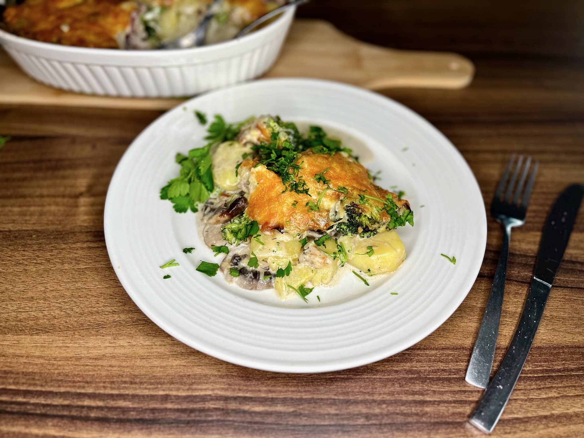 A portion of Broccoli and Mushroom Potato Casserole on a plate, garnished with fresh parsley