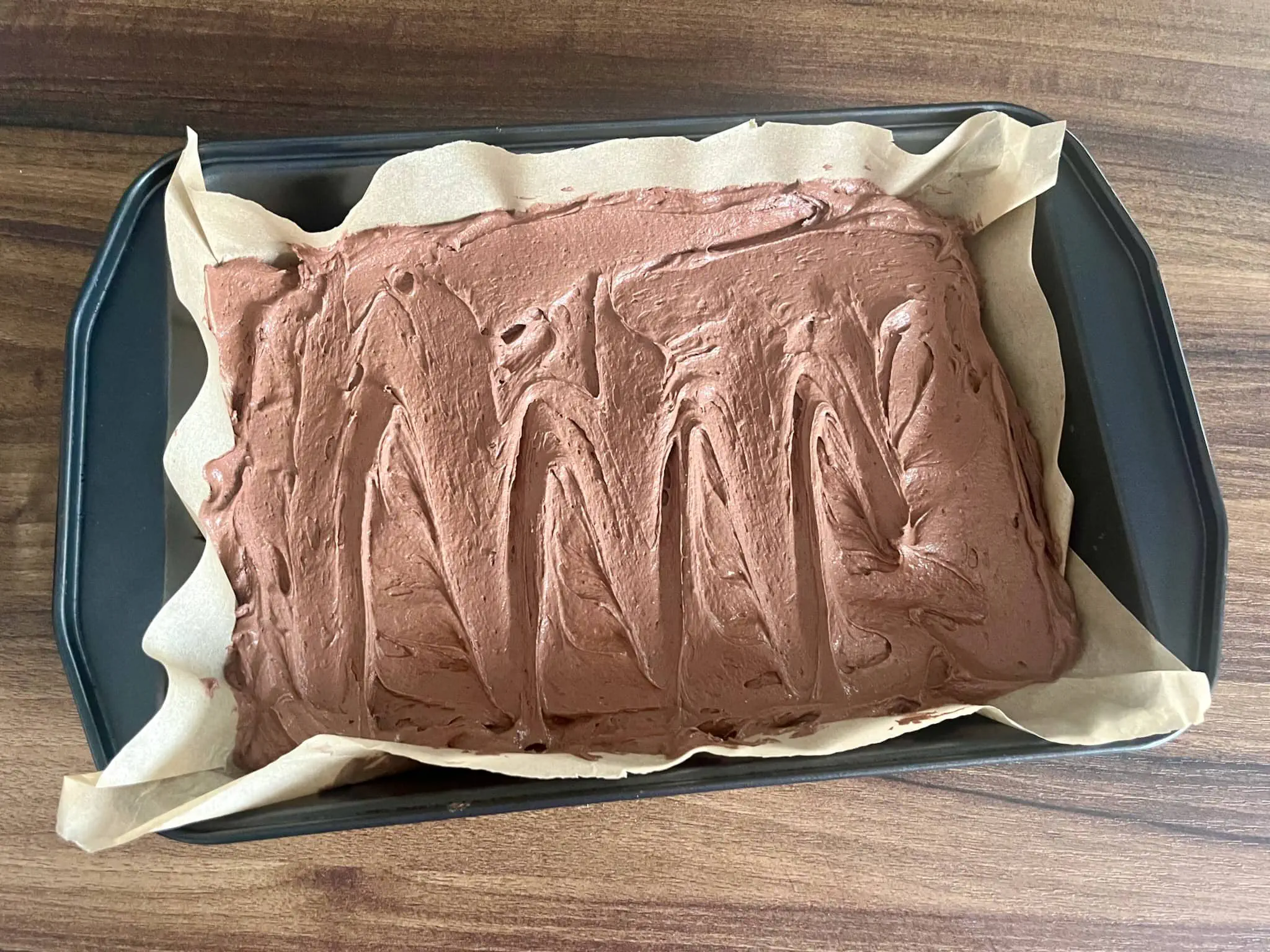The dough is spread evenly in a baking tray lined with baking parchment