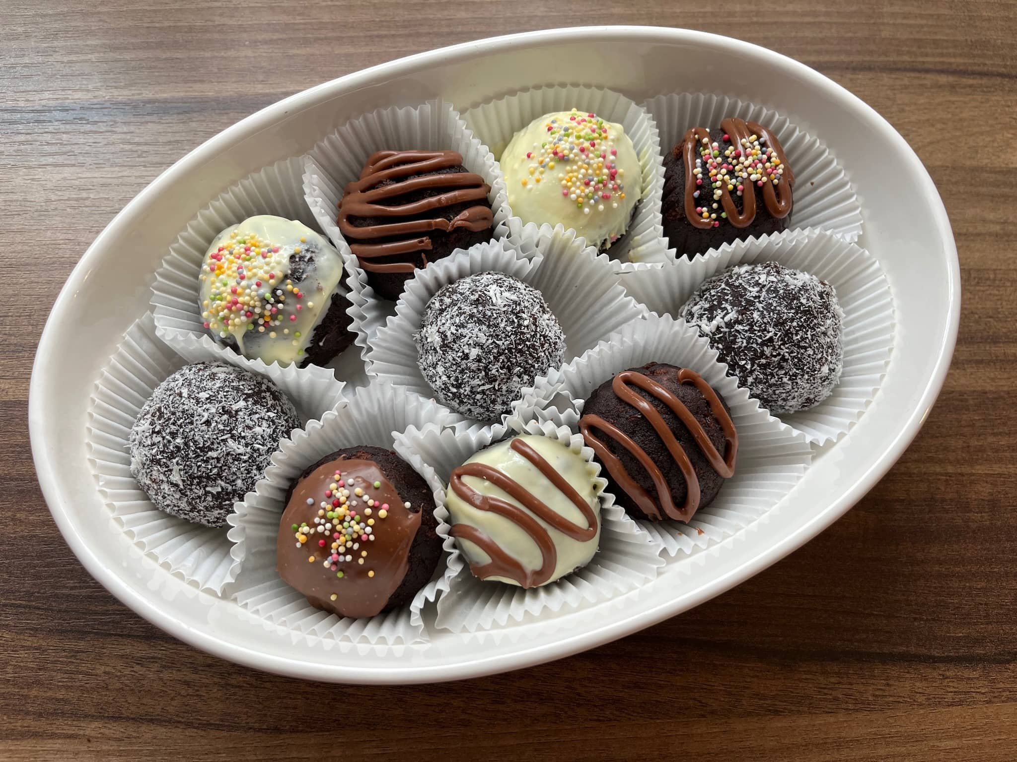 Decorated cake balls in muffin cases on a plate