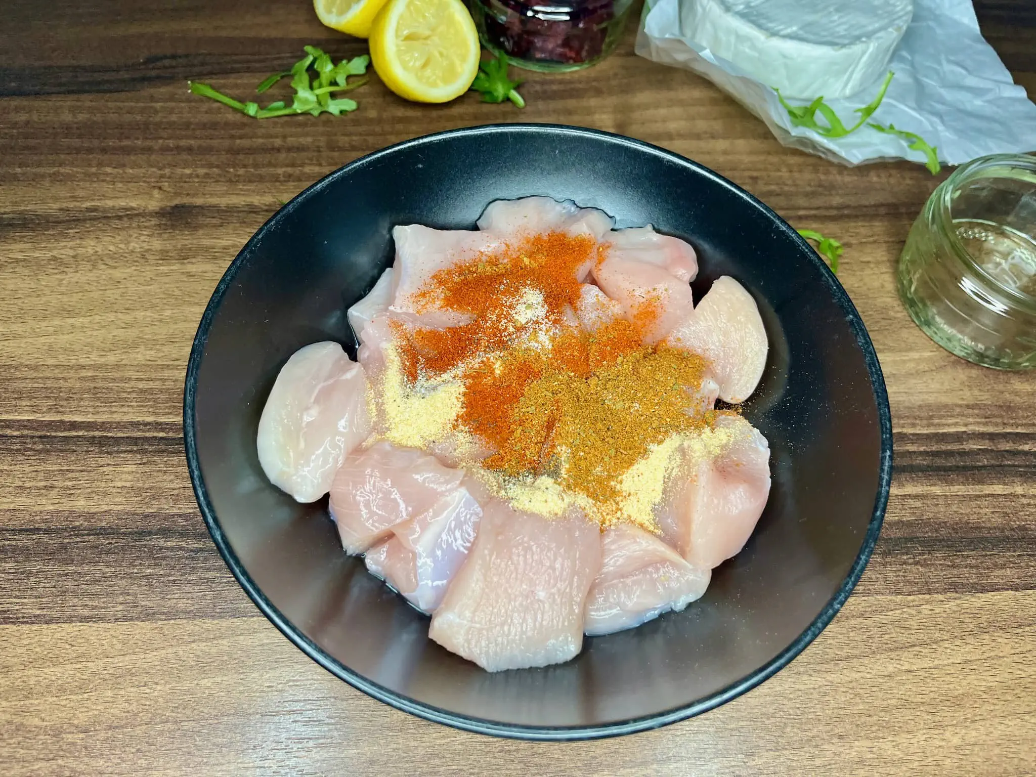 Diced chicken breast in a bowl with spices on the top