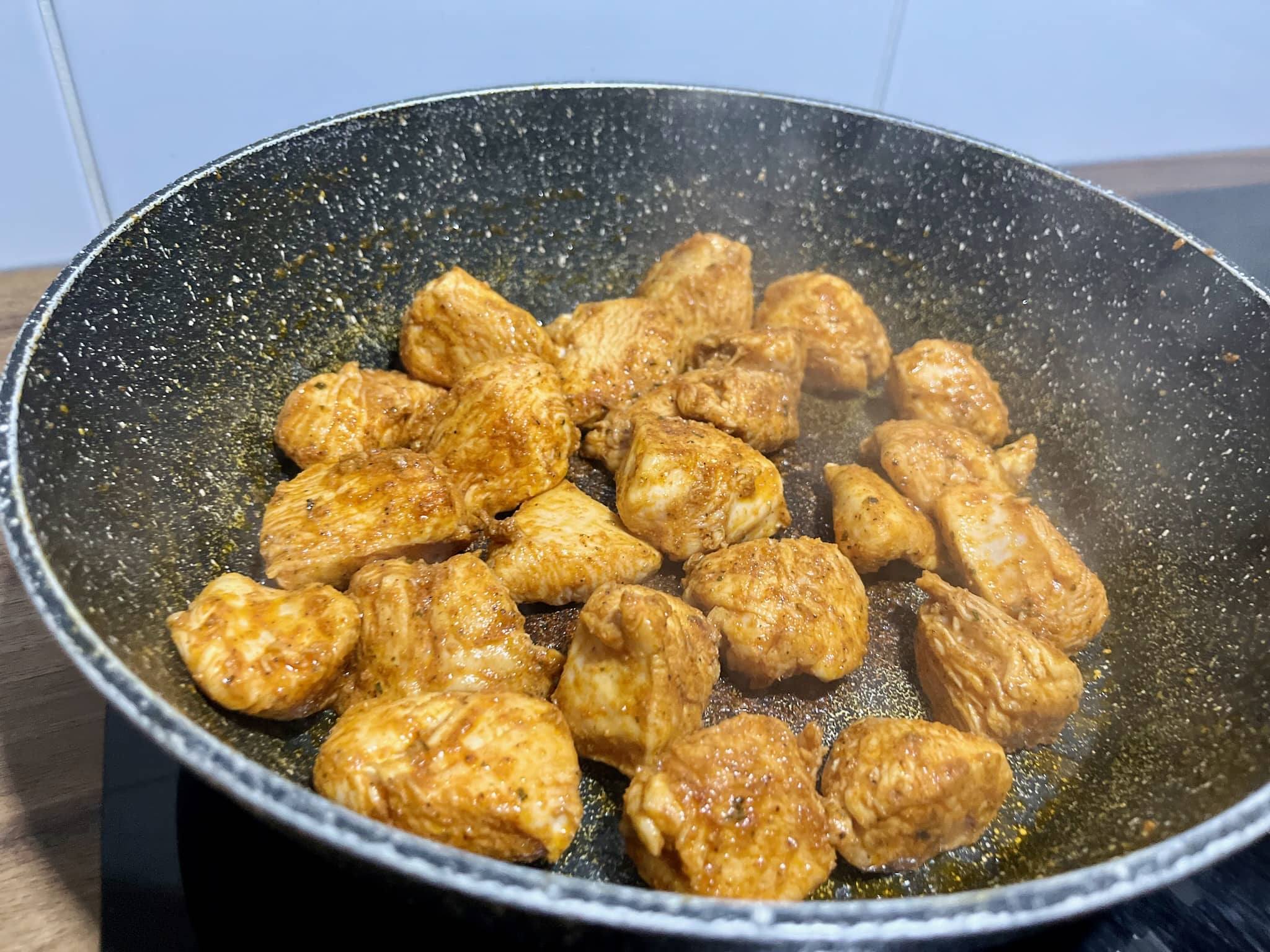 Diced chicken frying in a pan