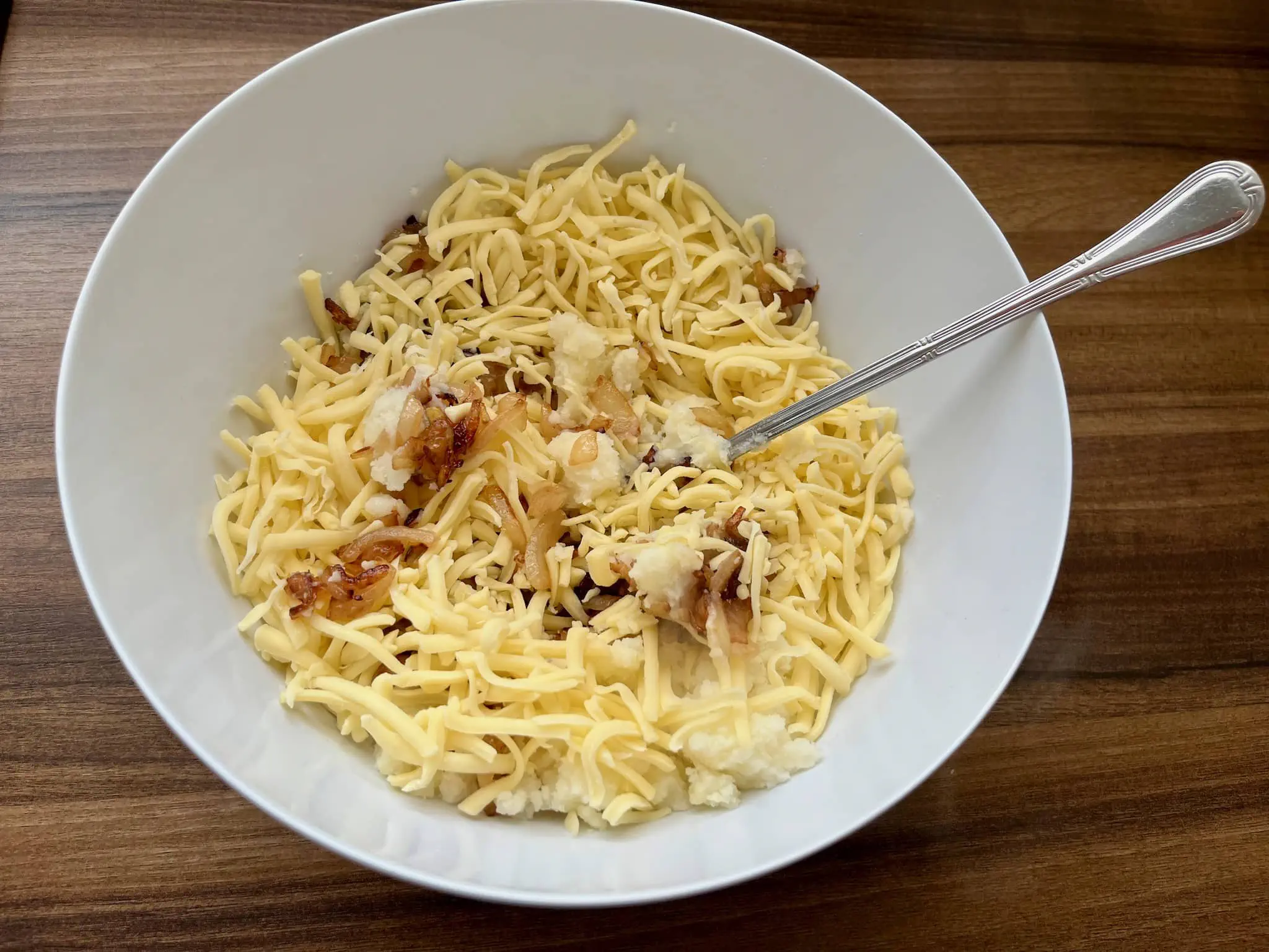 Mashed potatoes with seasonings, onion and grated cheese in a bowl