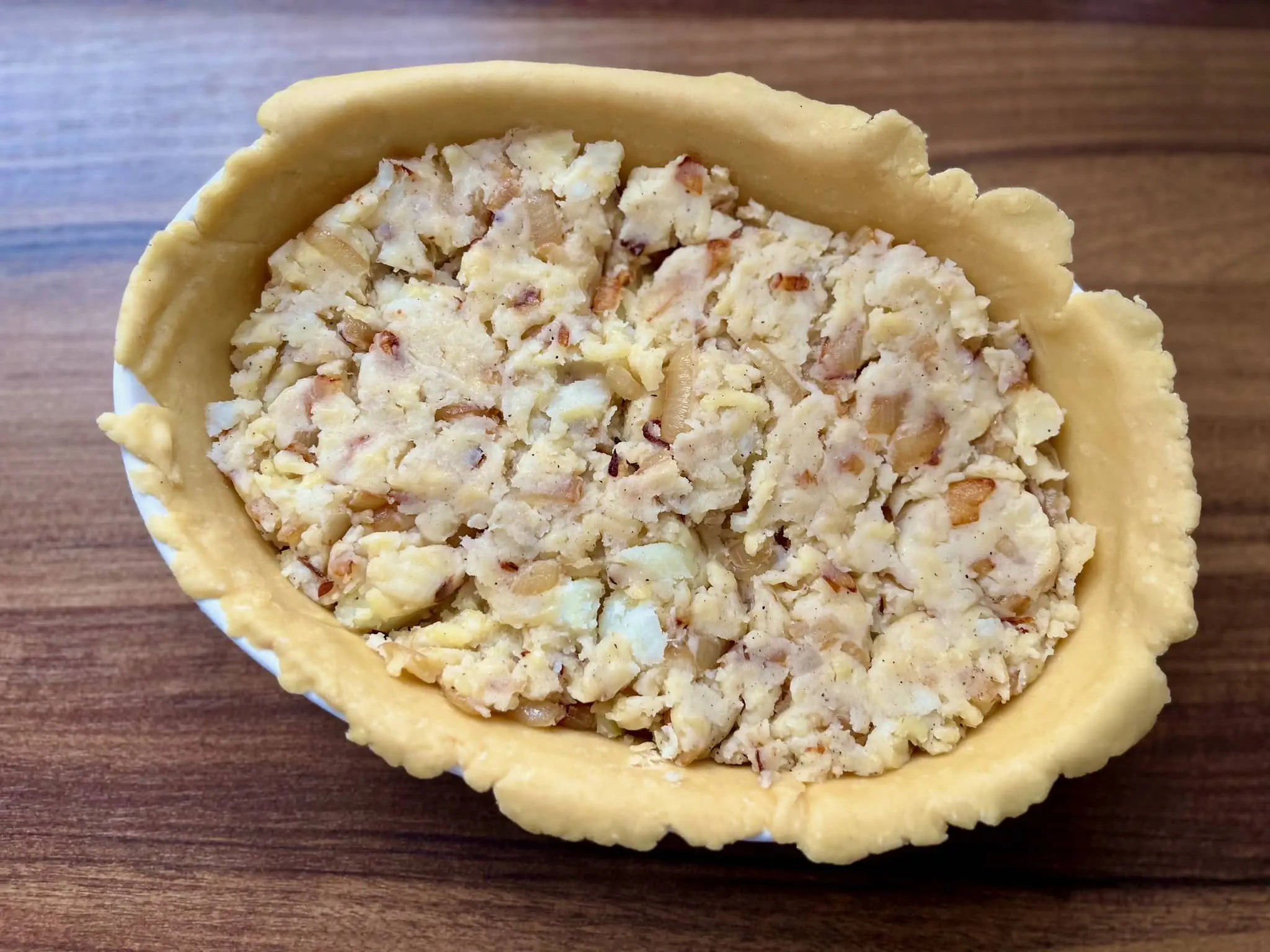 Ovenproof dish lined with piue crust and filled with cheese and onion filling