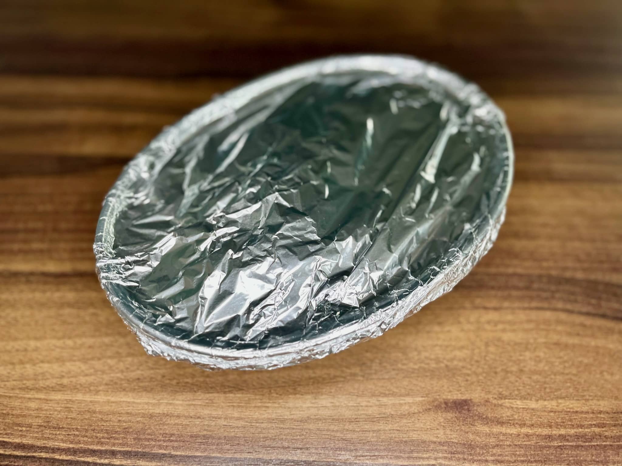 A disk for Cheesy Baked Potatoes covered with tin foil ready to put into the oven