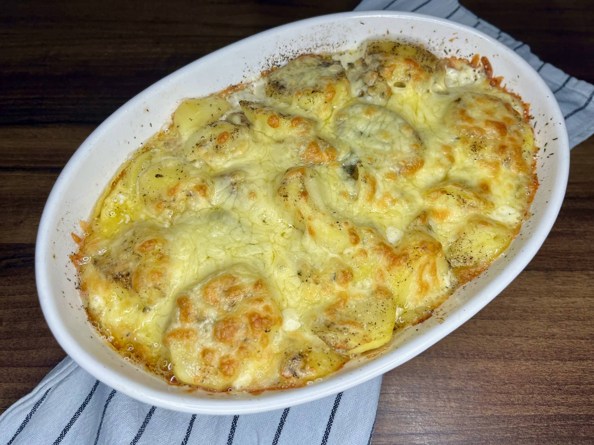 Nicely baked Cheesy Baked Potatoes with Pancetta in an ovenproof dish