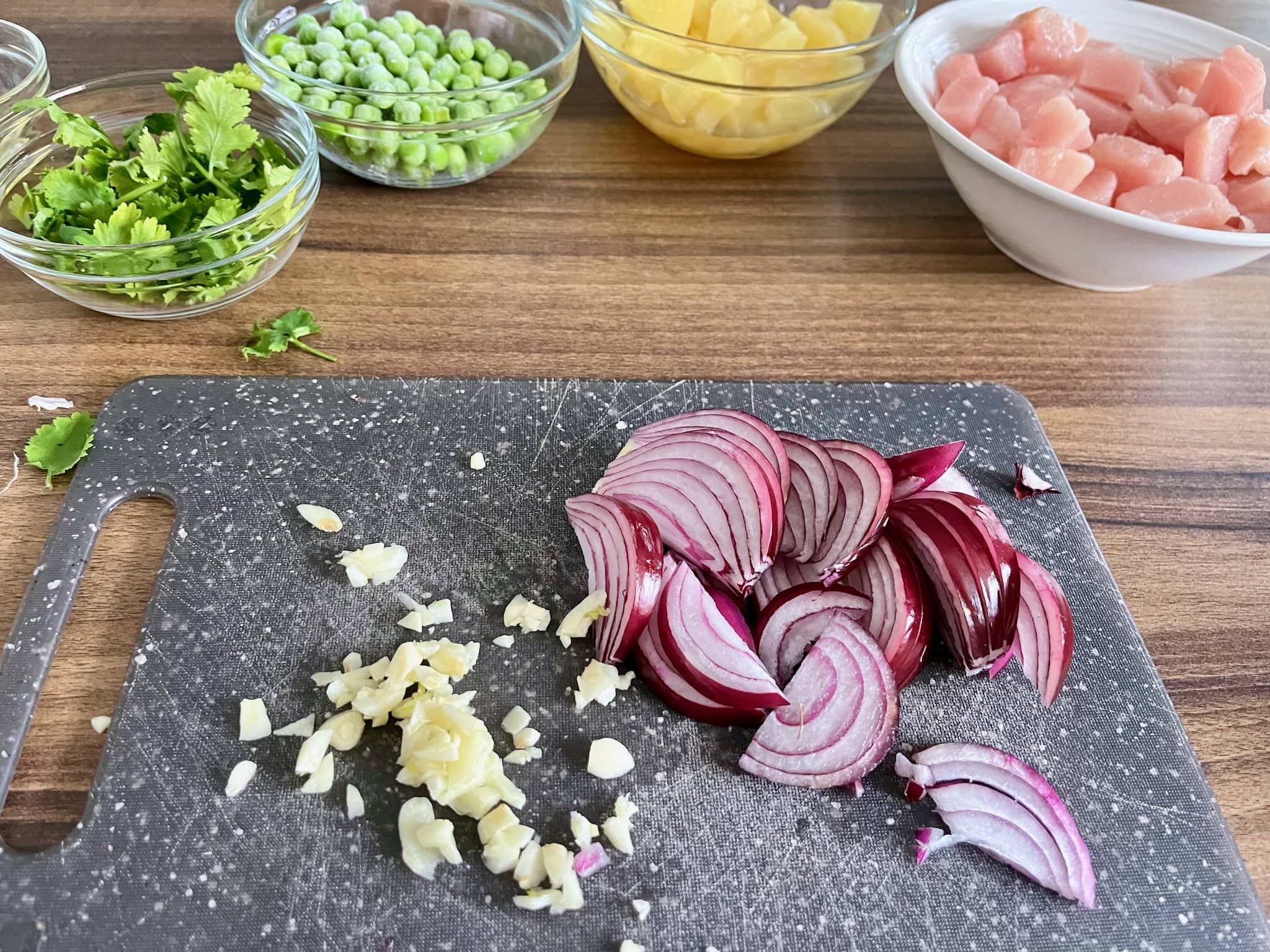 Chopped garlic and red onion sit on a cutting board