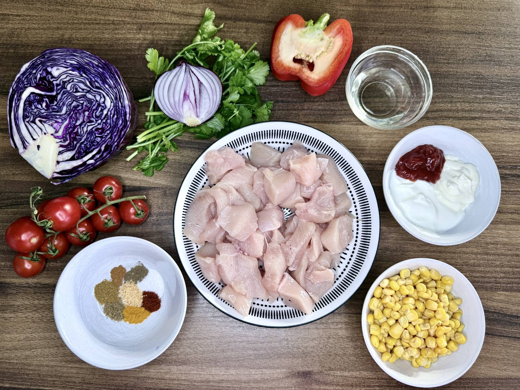 All the ingredients on a tabletop, with diced chicken breast, ready to make Chicken Kebab Salad