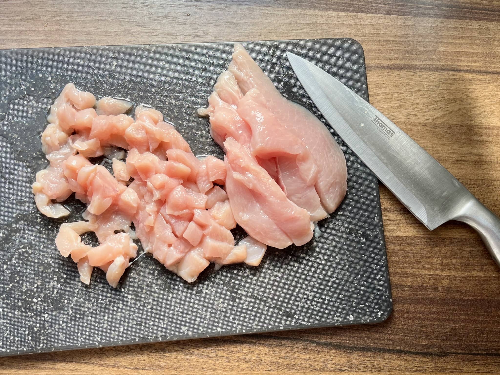 Chicken breast on a chopping board choppes into small cubes