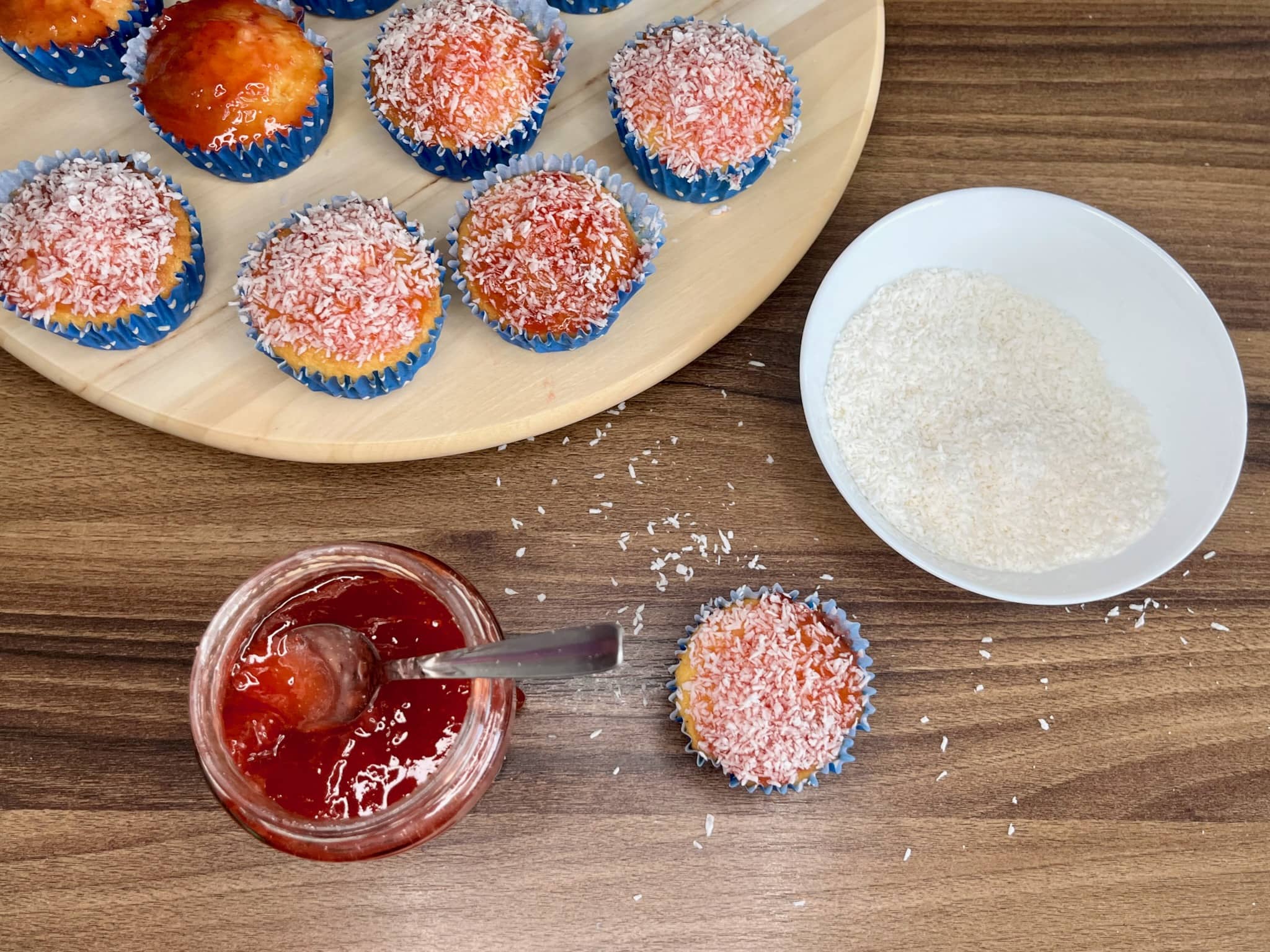Sprinkle coconut flakes on top of muffins that have been brushed with strawberry jam.