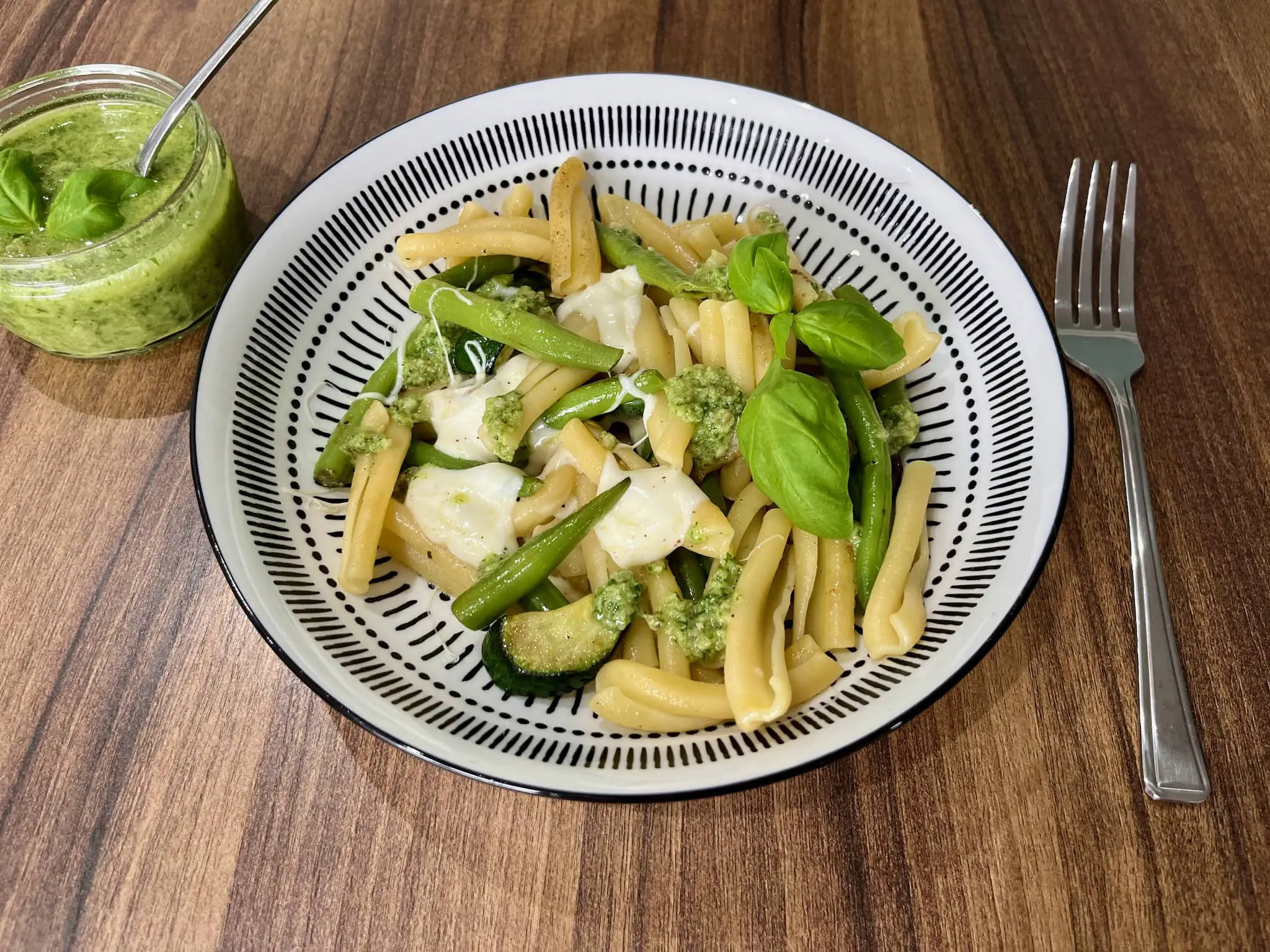 Makaron z cukinią i fasolką szparagową na talerzu podany z pesto bazyliowym