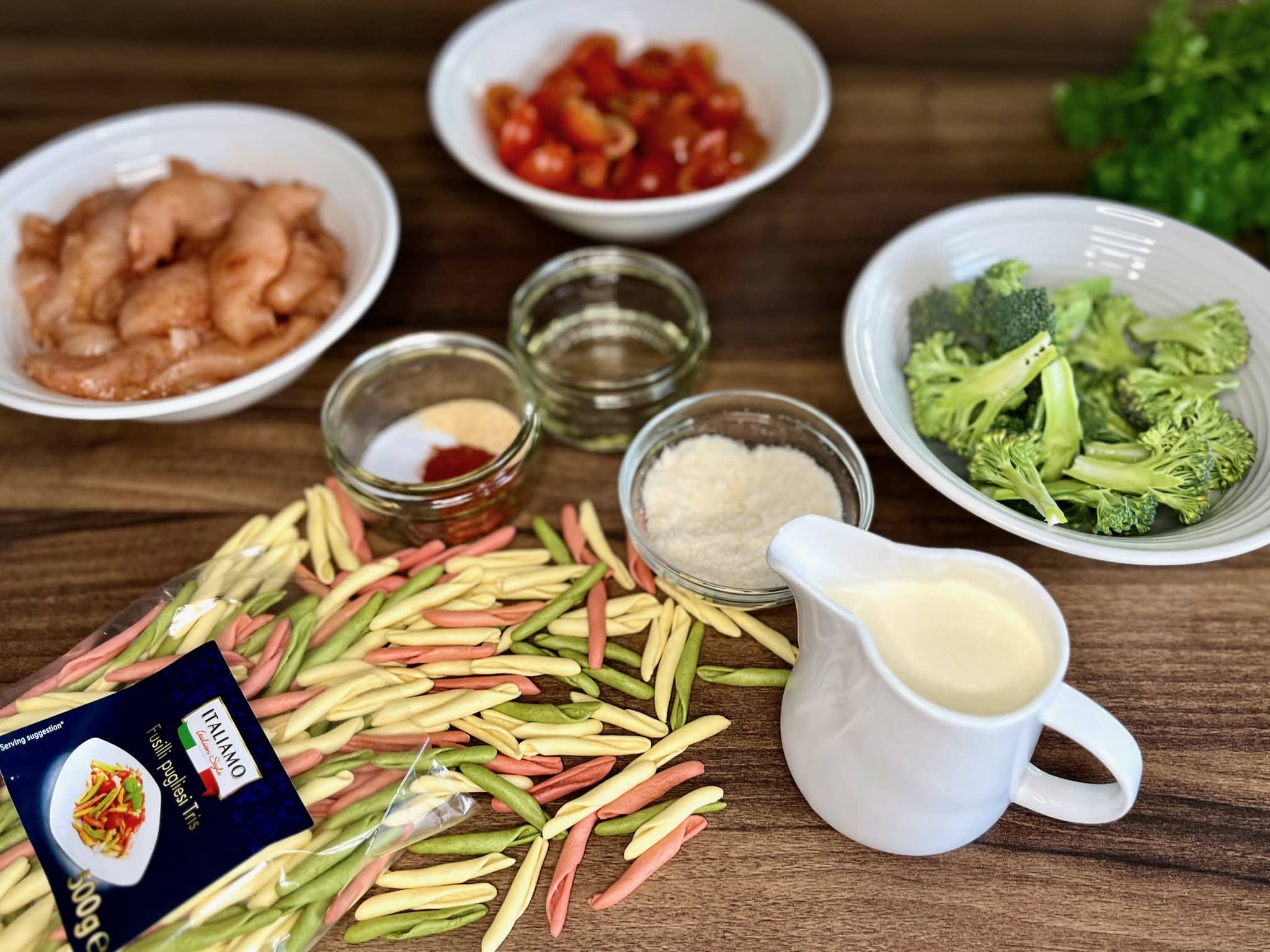 The ingredients for Creamy Chicken Pasta with Cherry Tomatoes are all laid out on the kitchen table, ready to be cooked.