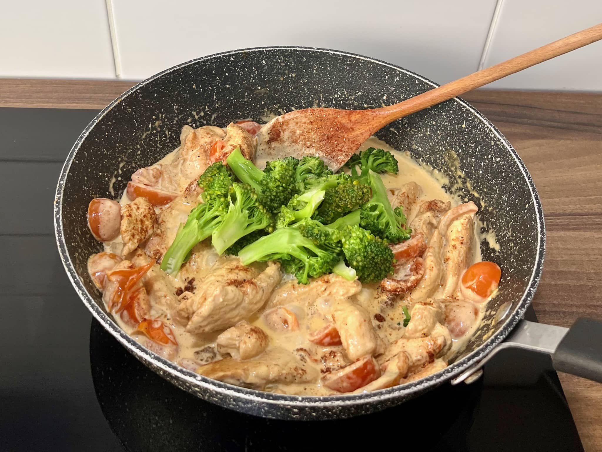 Broccoli florets added to chicken and cherry tomatoes in a large skillet, cooked until tender.