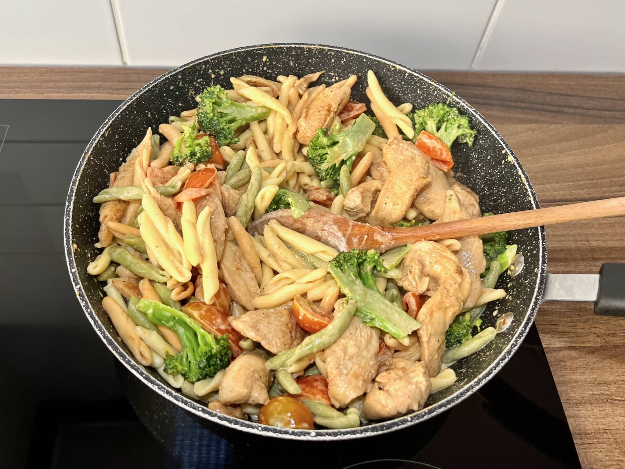 Pasta, broccoli, chicken, and cherry tomatoes cooked together in a large skillet until heated through.