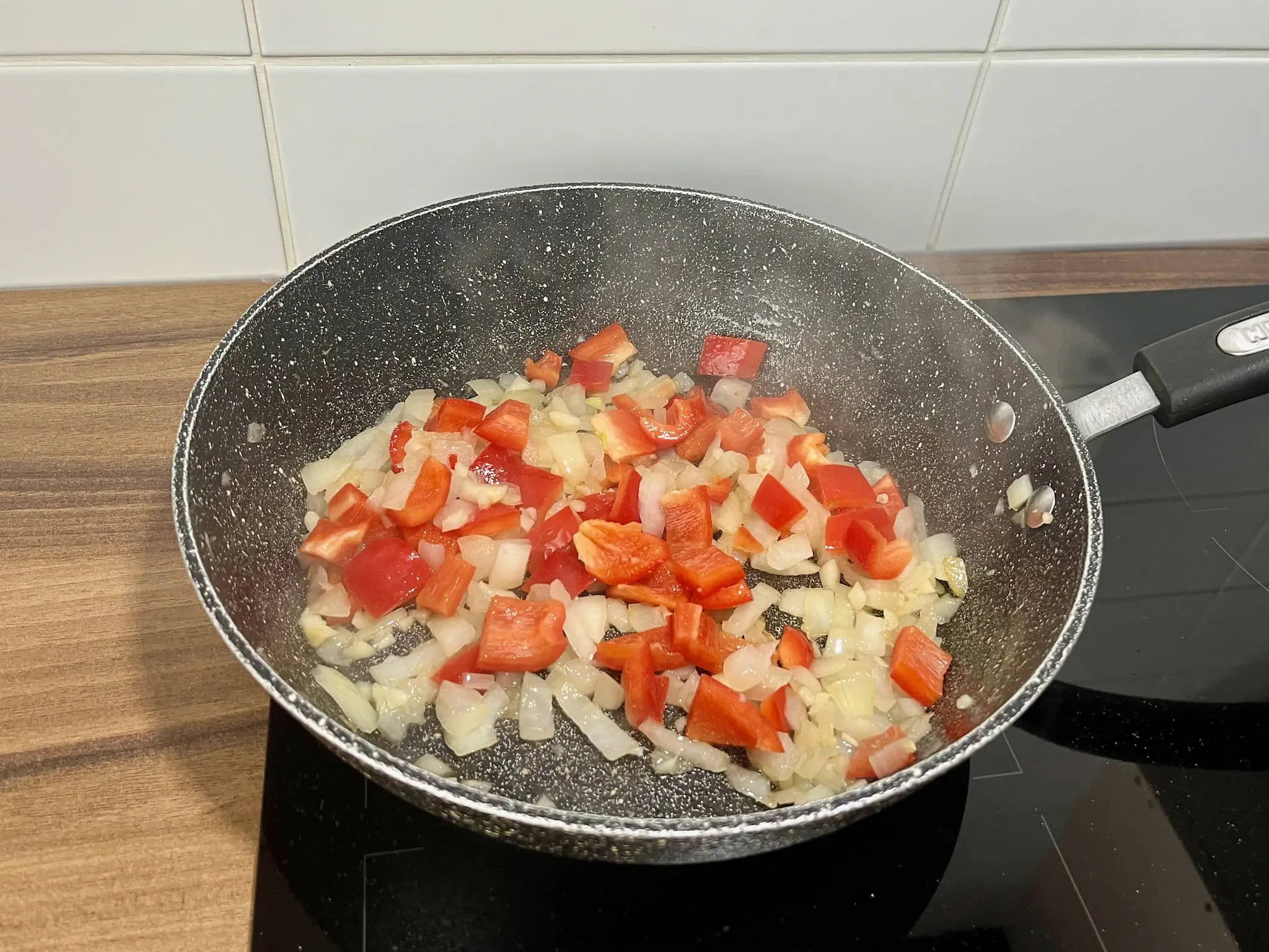 Cebula, czosnek i papryka smażące się na patelni