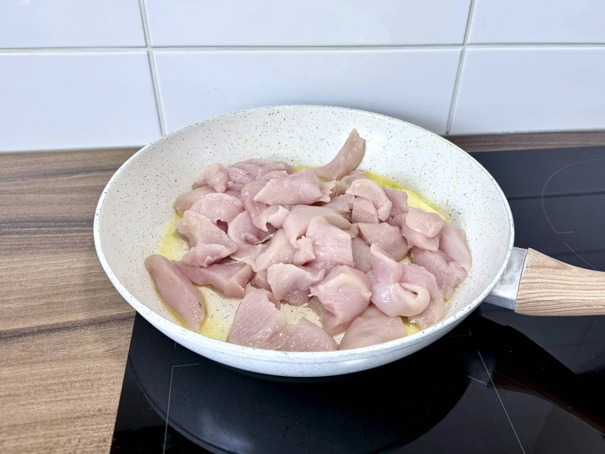 Chicken breast chunks added to melted butter in the pan