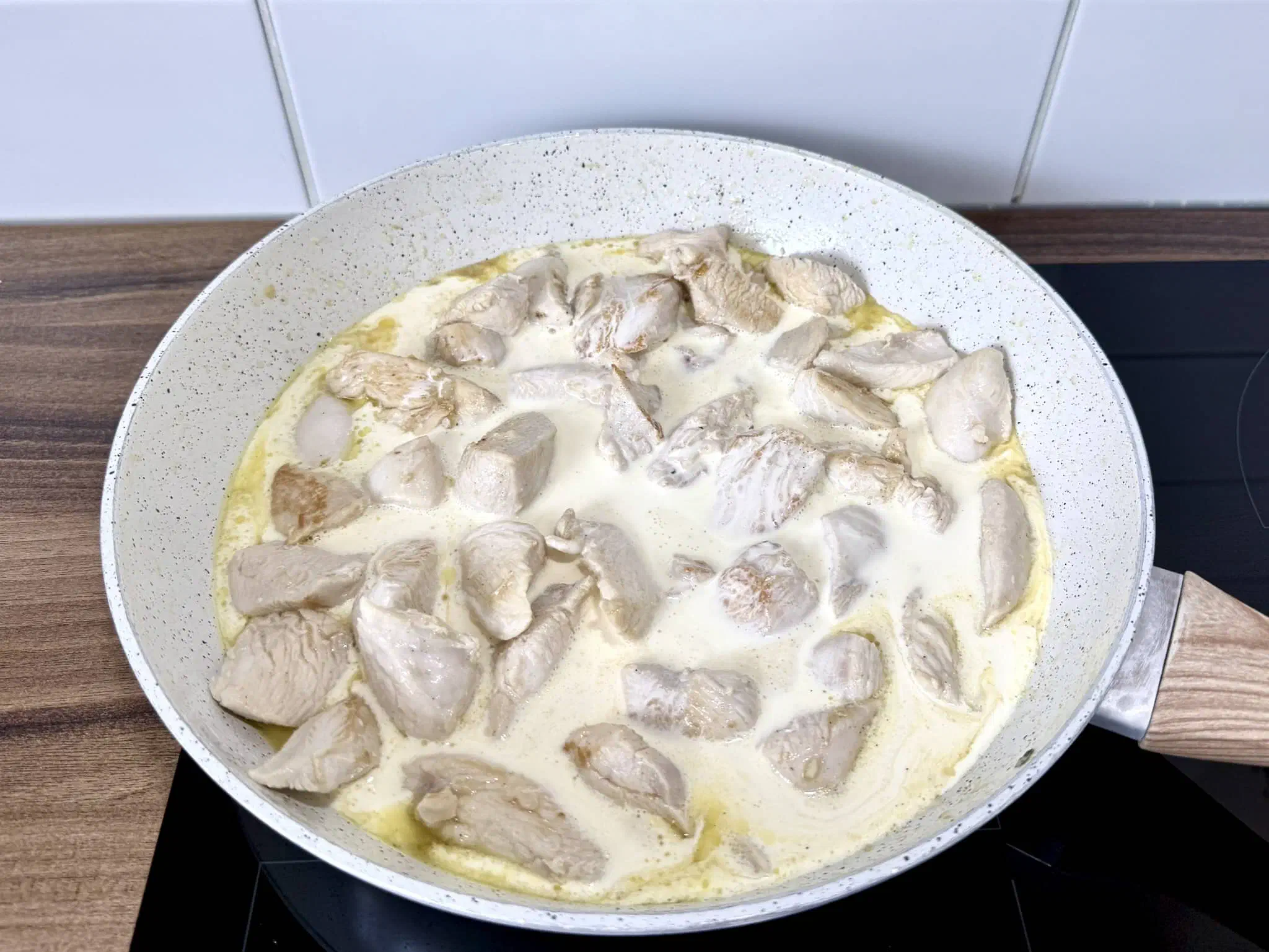 Chicken breast chunks cooking in a garlic sauce in the pan