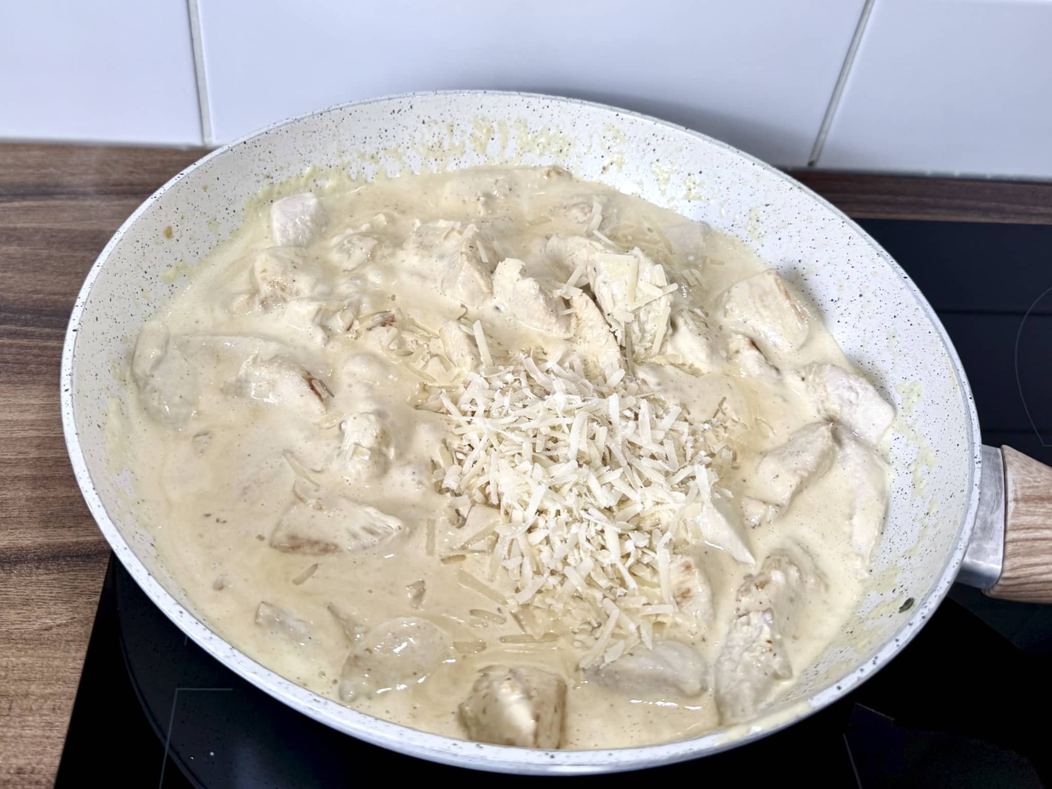 Parmesan cheese added to the chicken breast chunks in the pan
