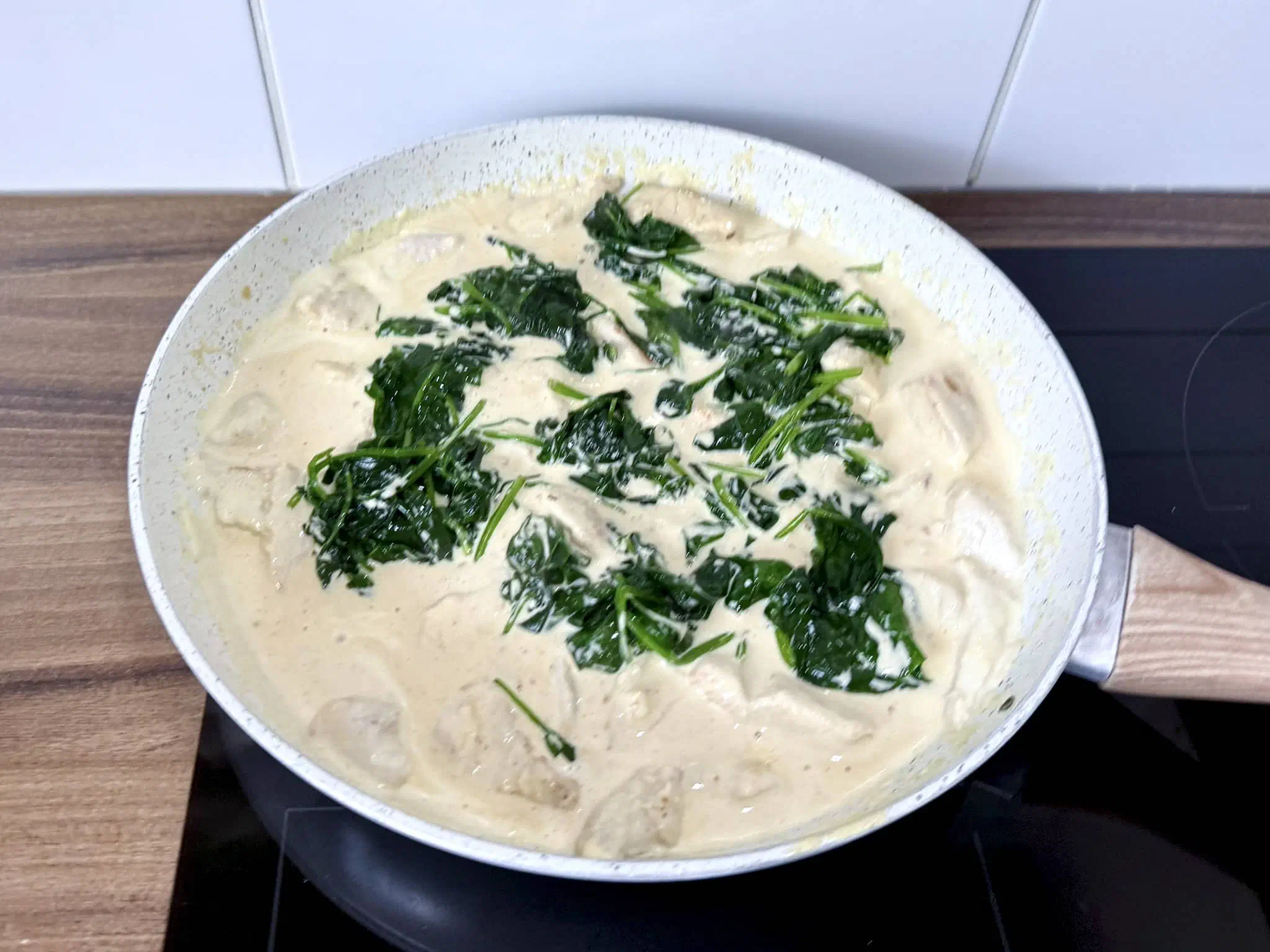 Wilted spinach added to the pan with the chicken chunks