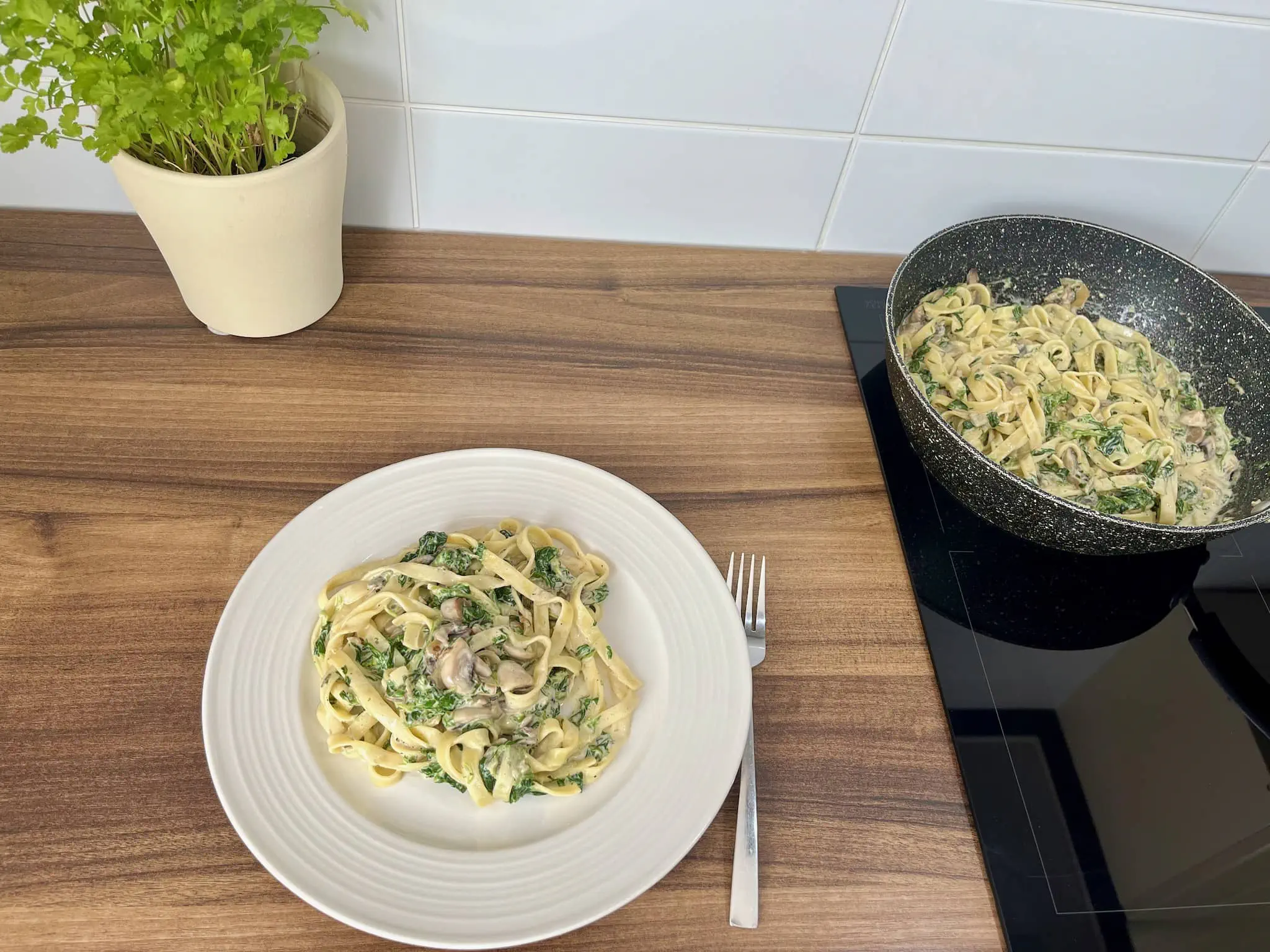 Porcja Kremowego Tagliatelle z Pieczarkami i Szpinakiem na talerzu, reszta na patelni
