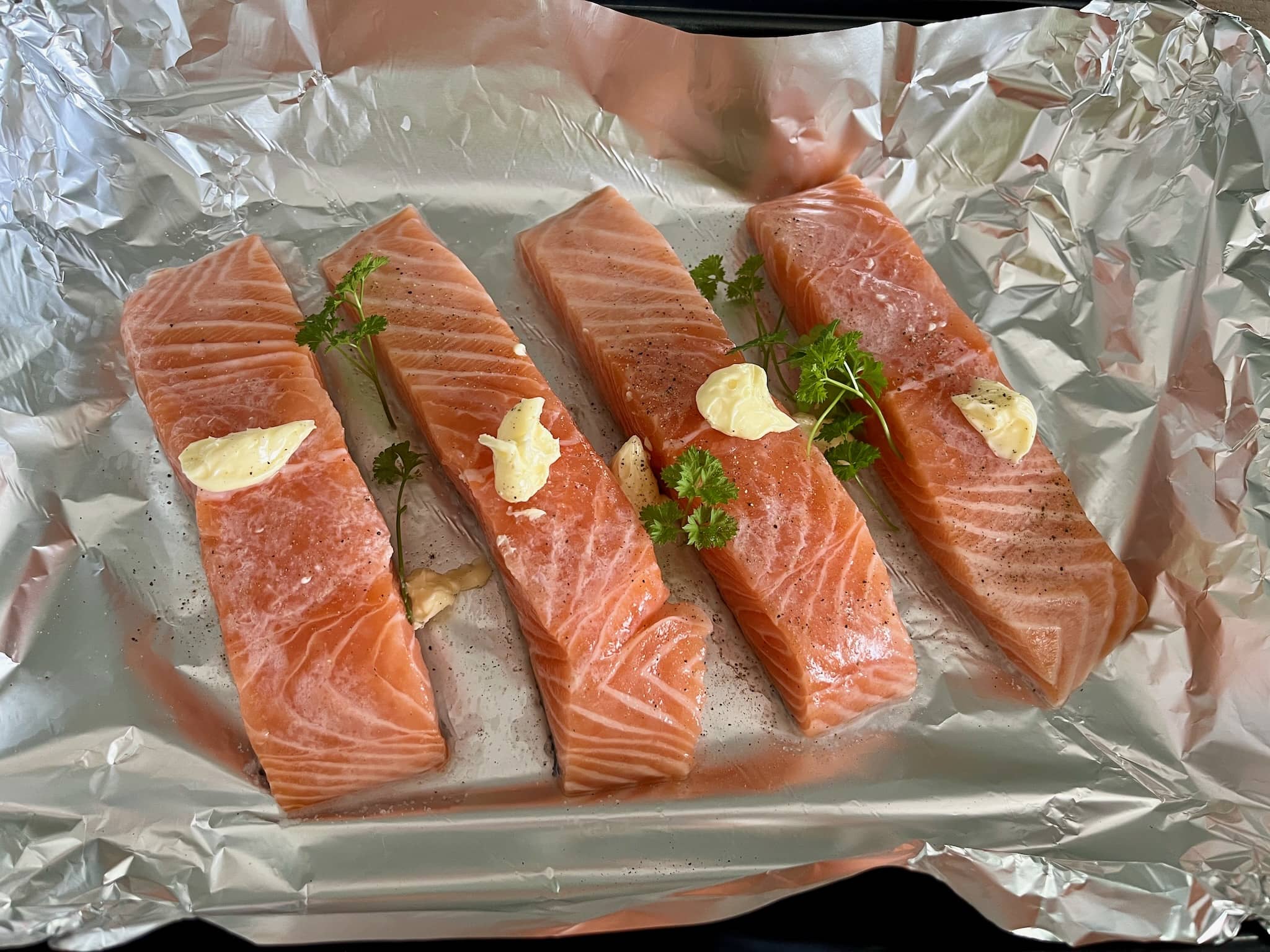 Seasoned salmon with butter on top placed on the tray ready to be cooked