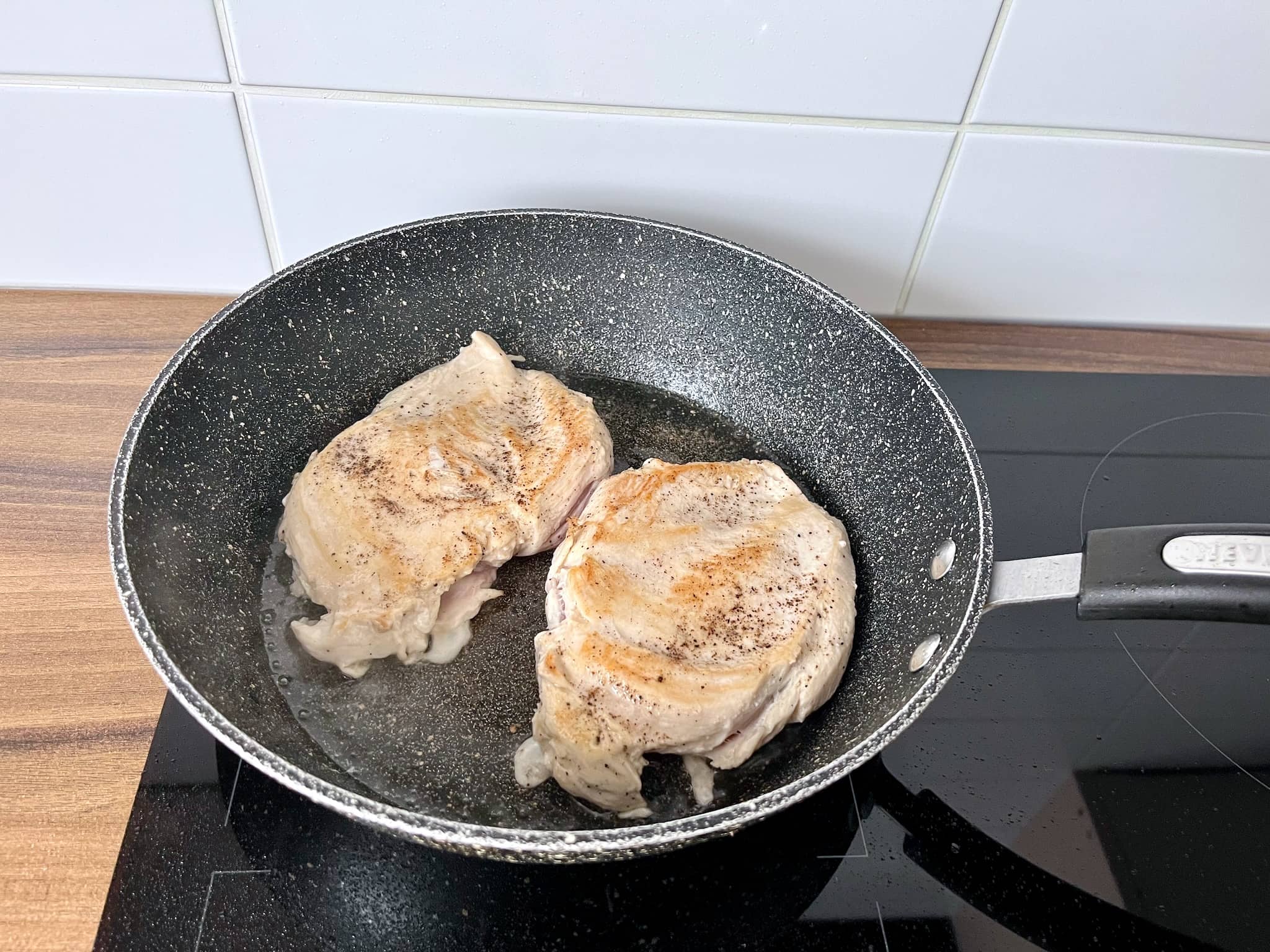 Chicken breasts frying in a pan