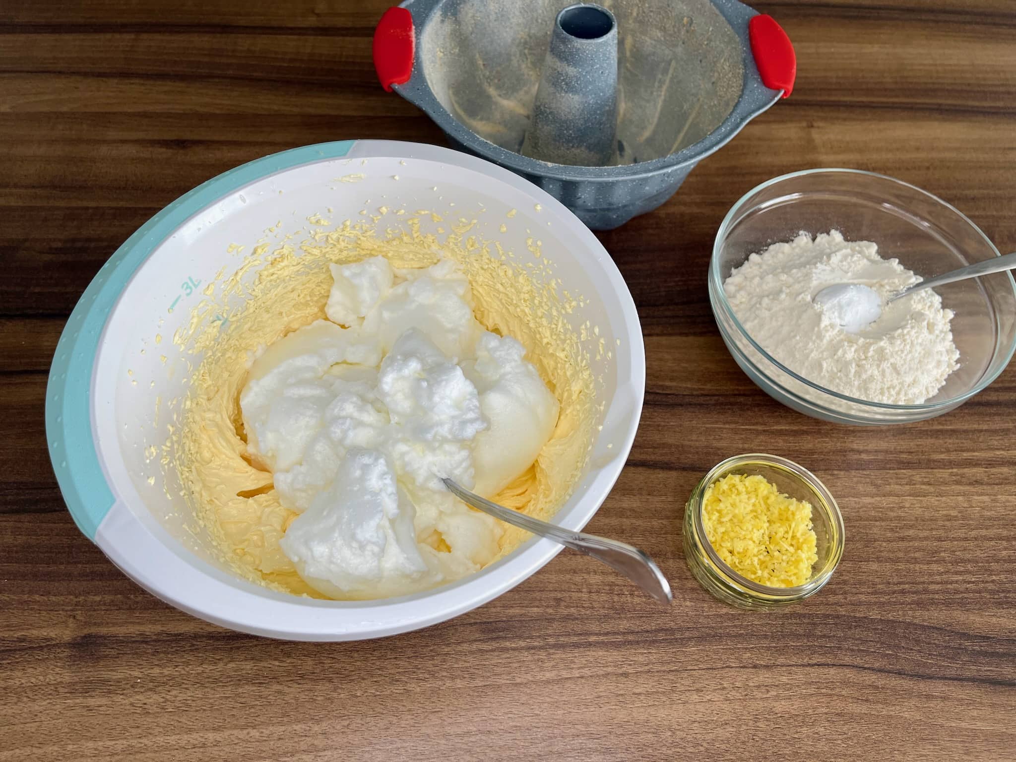Yolks mixed with sugar and butter with added mixed egg whites in a bowl